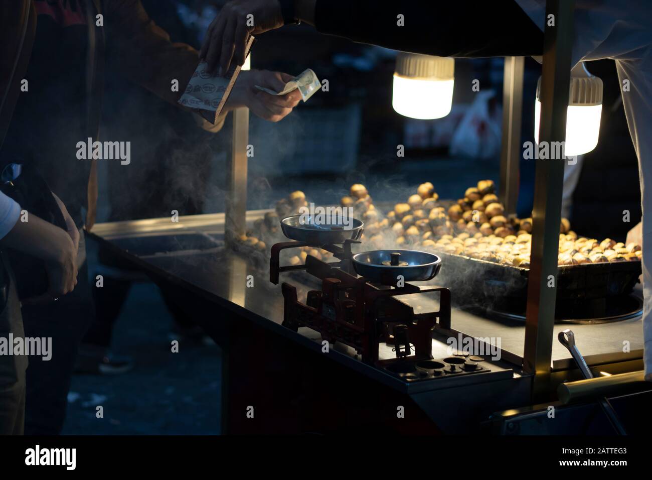 Mann, der gekochten Mais und Kastanien im Wagen verkauft. Abends fotografiert.Nahaufnahme Stockfoto