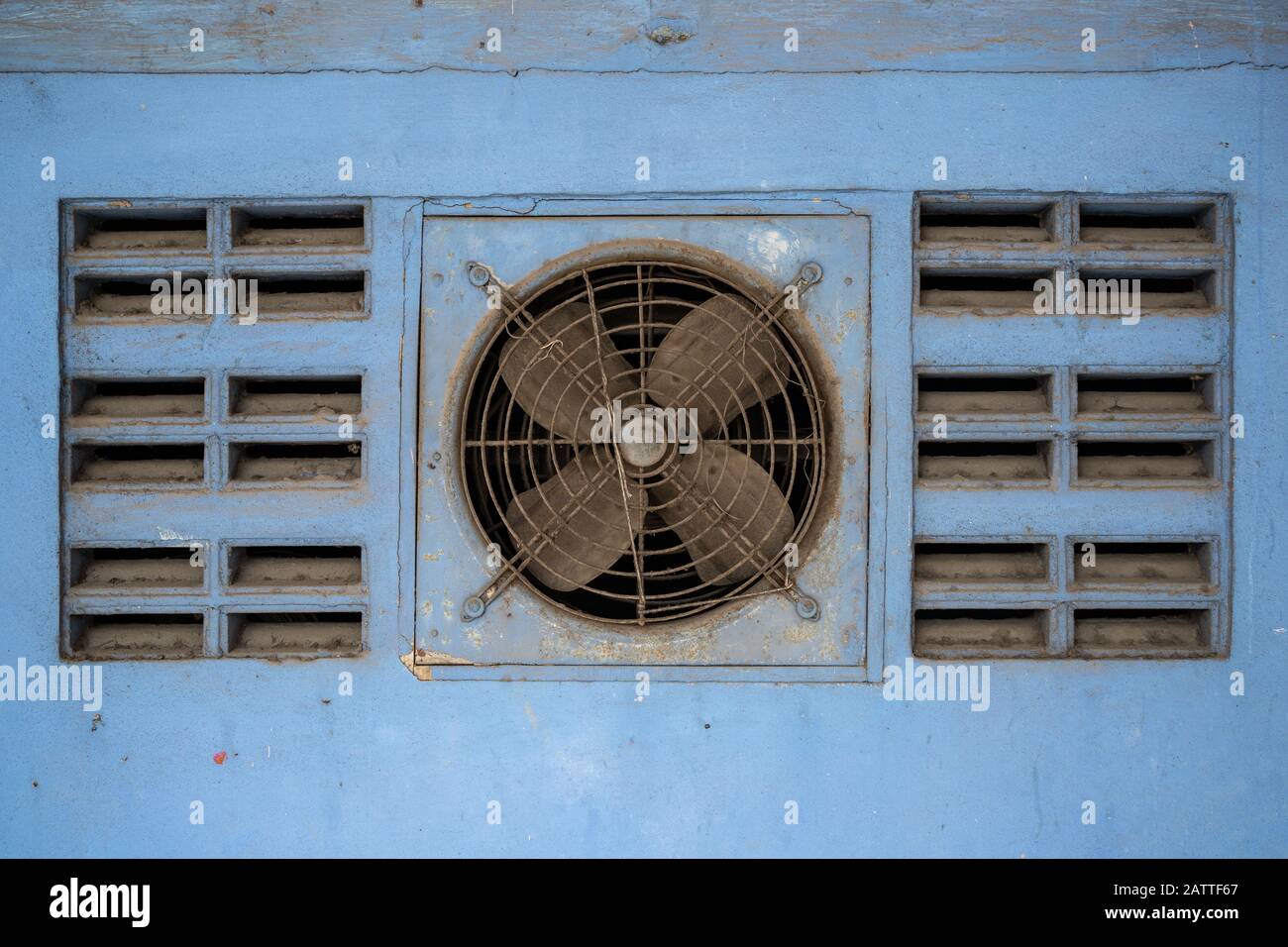 Staubiger Ventilator an der blauen Wand Stockfoto