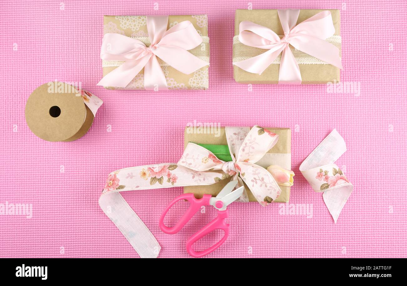 Geschenke verpackt in Kraftpapier und rosafarbenen Bändern overhead flach für Muttertag, Geburtstag oder Valentinstag feiern legen. Stockfoto