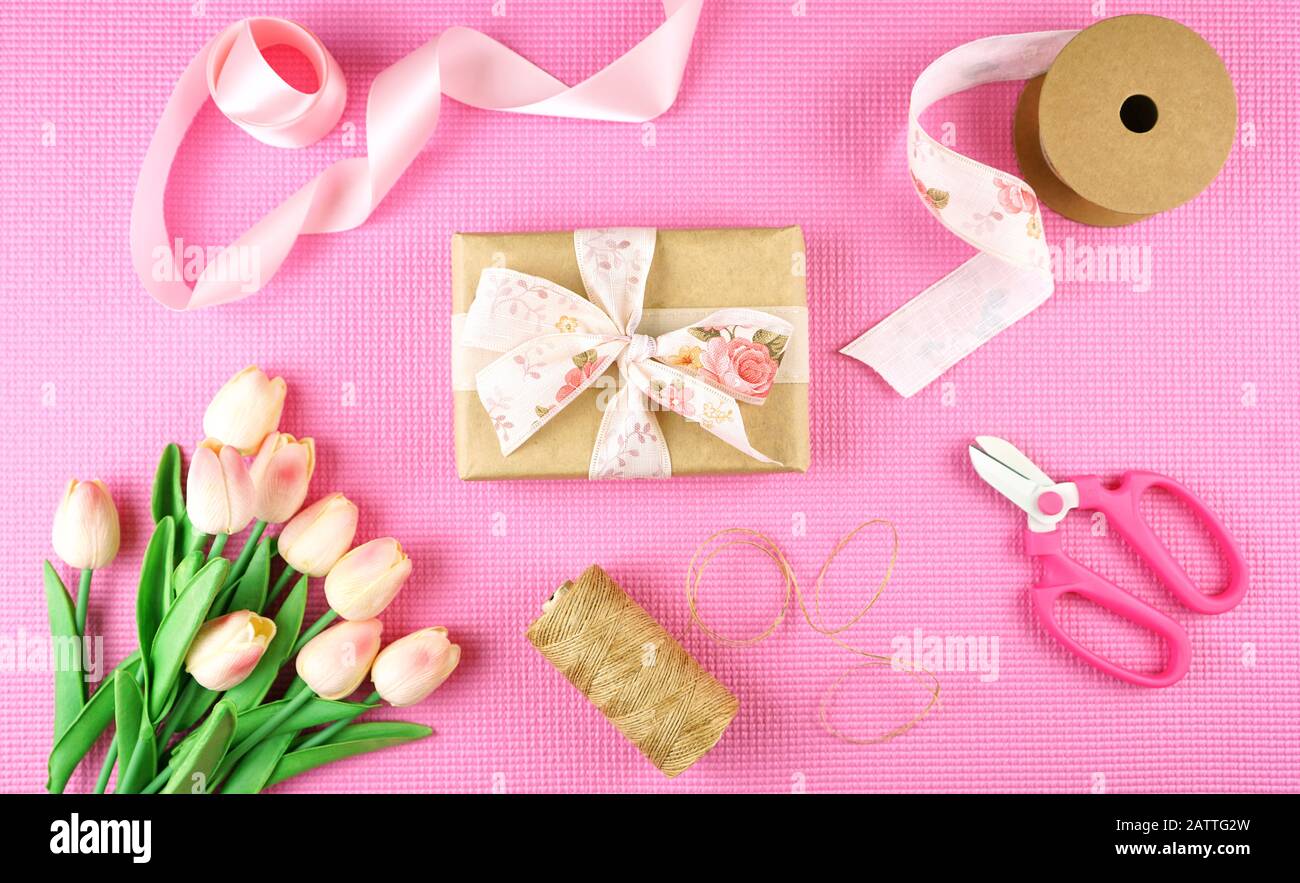 Geschenke verpackt in Kraftpapier und rosafarbenen Bändern overhead flach für Muttertag, Geburtstag oder Valentinstag feiern legen. Stockfoto