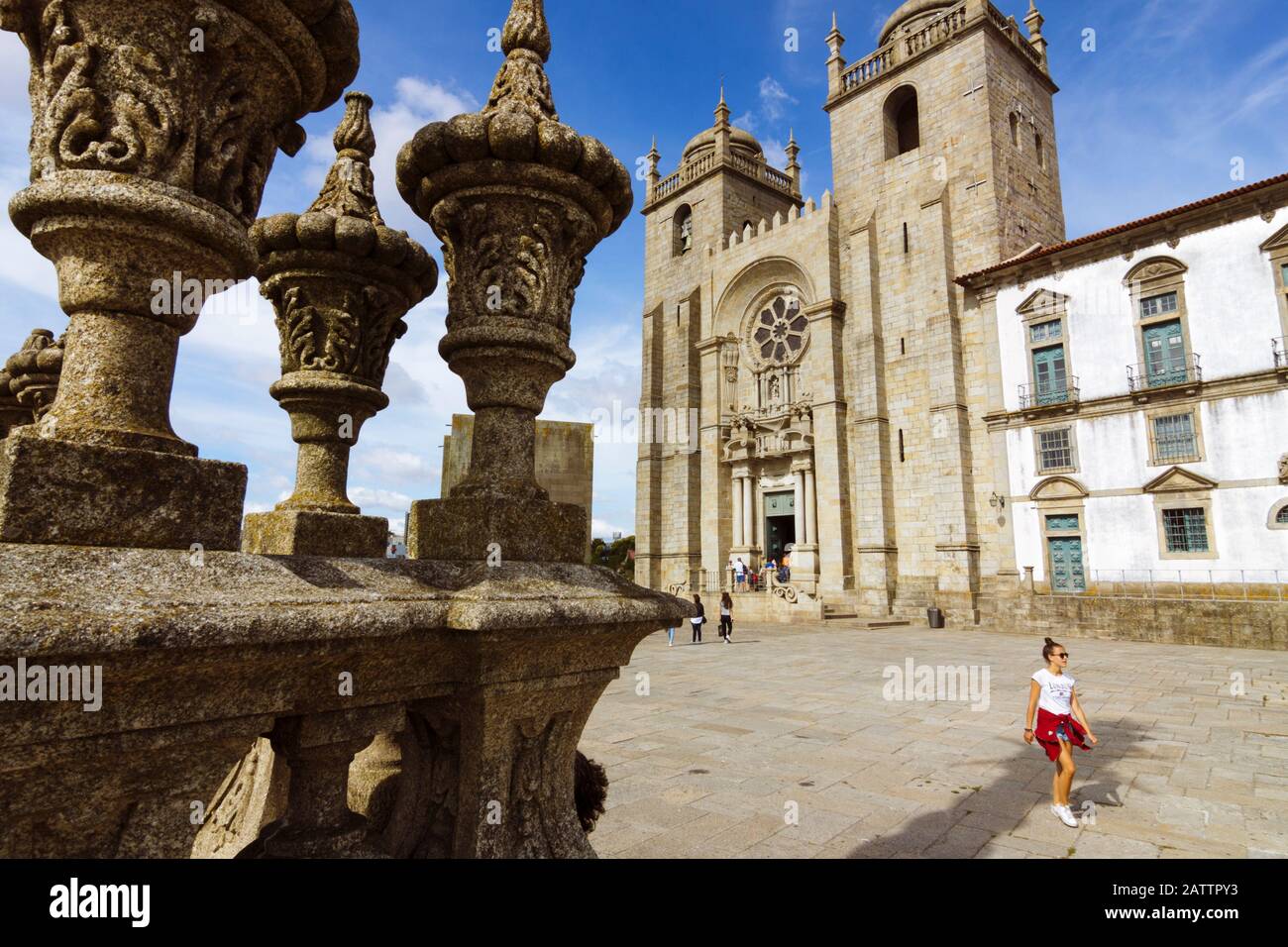 Porto, Portugal: EINE junge Frau spaziert an der Kathedrale von Porto vorbei, die im 12. Jahrhundert erbaut wurde, mit Umbauten im Stil des Barock und des 20. Jahrhunderts. Stockfoto