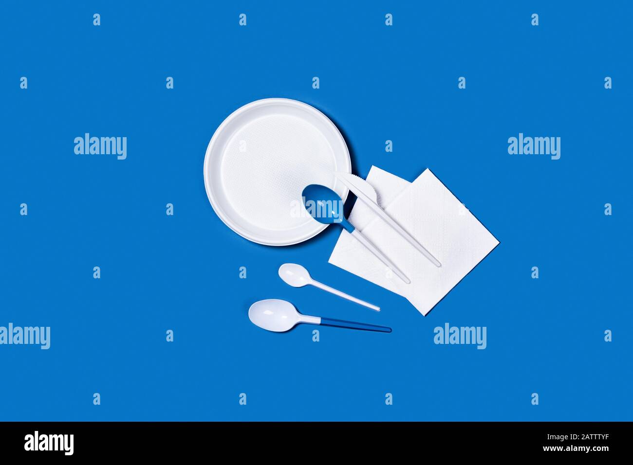 Abbildung der weißen Kunststofflöffel und -Platten auf blauem Hintergrund. Flaches Layout, Draufsicht, Kopierbereich. Stockfoto