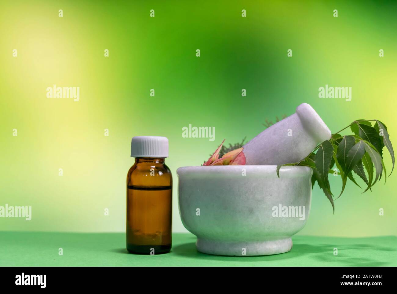 Klassisches Homöopathiekonzept - Heilkräuter, rosafarbene Blume im Mörtel mit Homöopathika in brauner Flasche auf grünem Melange gelber Hintergrund Stockfoto