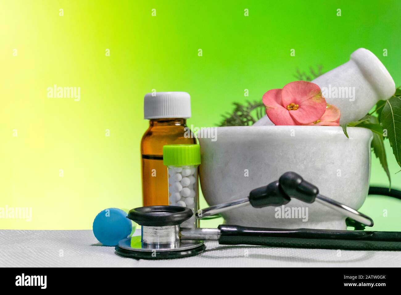 Alternatives Medizinkonzept - Homöopathische Heilkräuter mit Mörtel und Pfirsich mit Stethoskop sowie Flasche mit Pillen und flüssigem Homöopathikum Stockfoto