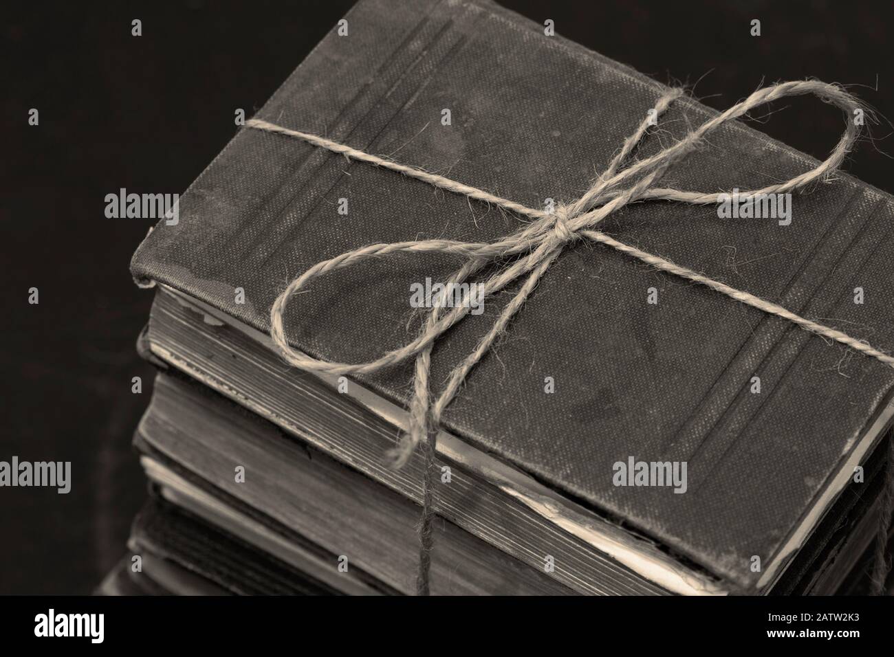 Antike alte Bücher, die in einen Haufen gestapelt sind, der mit einer Schnur verbunden ist. Mit Farbtonierung Stockfoto