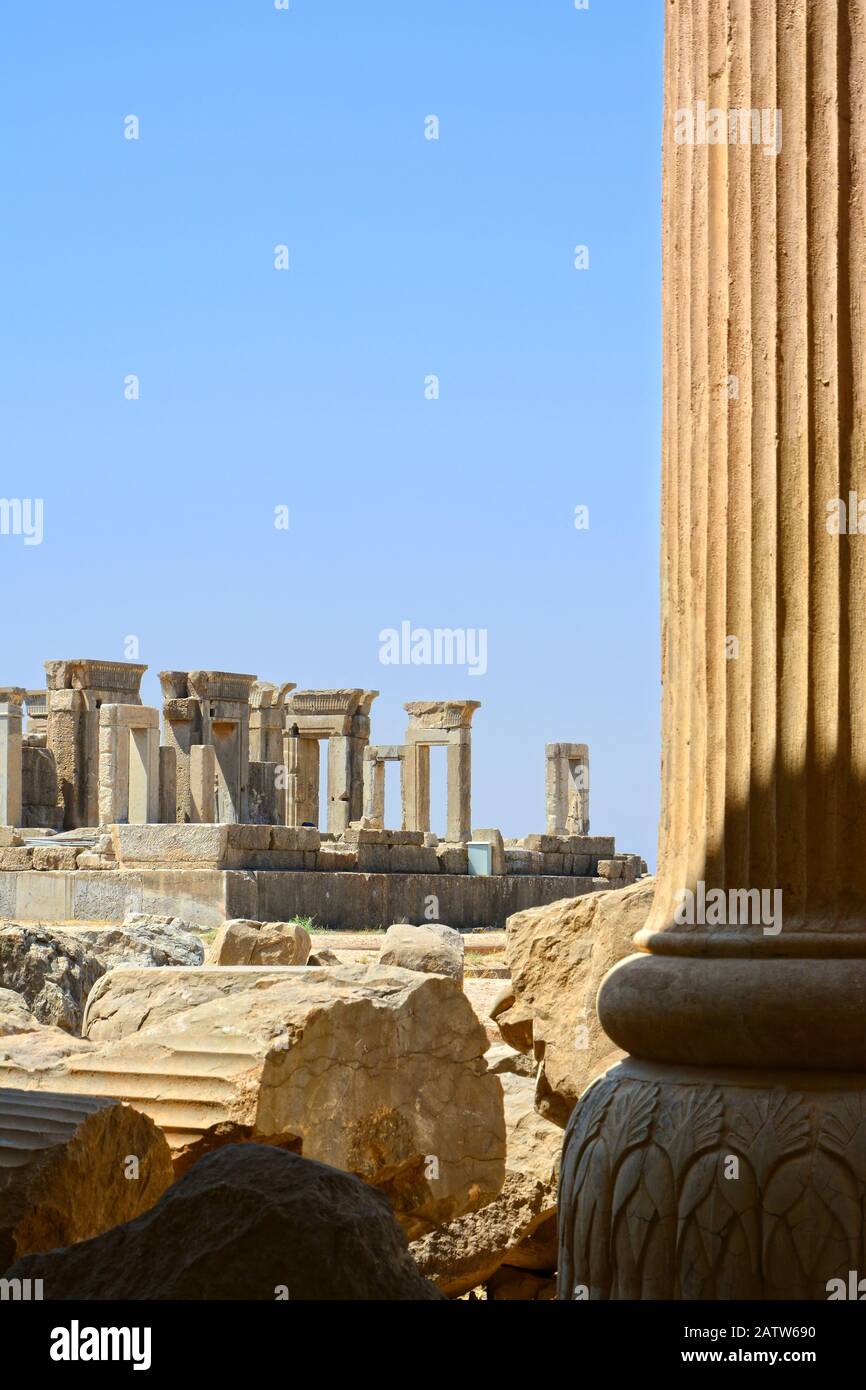 Eine Säule der Apadana-Halle von Persepolis im Vordergrund, mit teilweisem Blick auf den Palast von Darius in der Ferne. Stockfoto