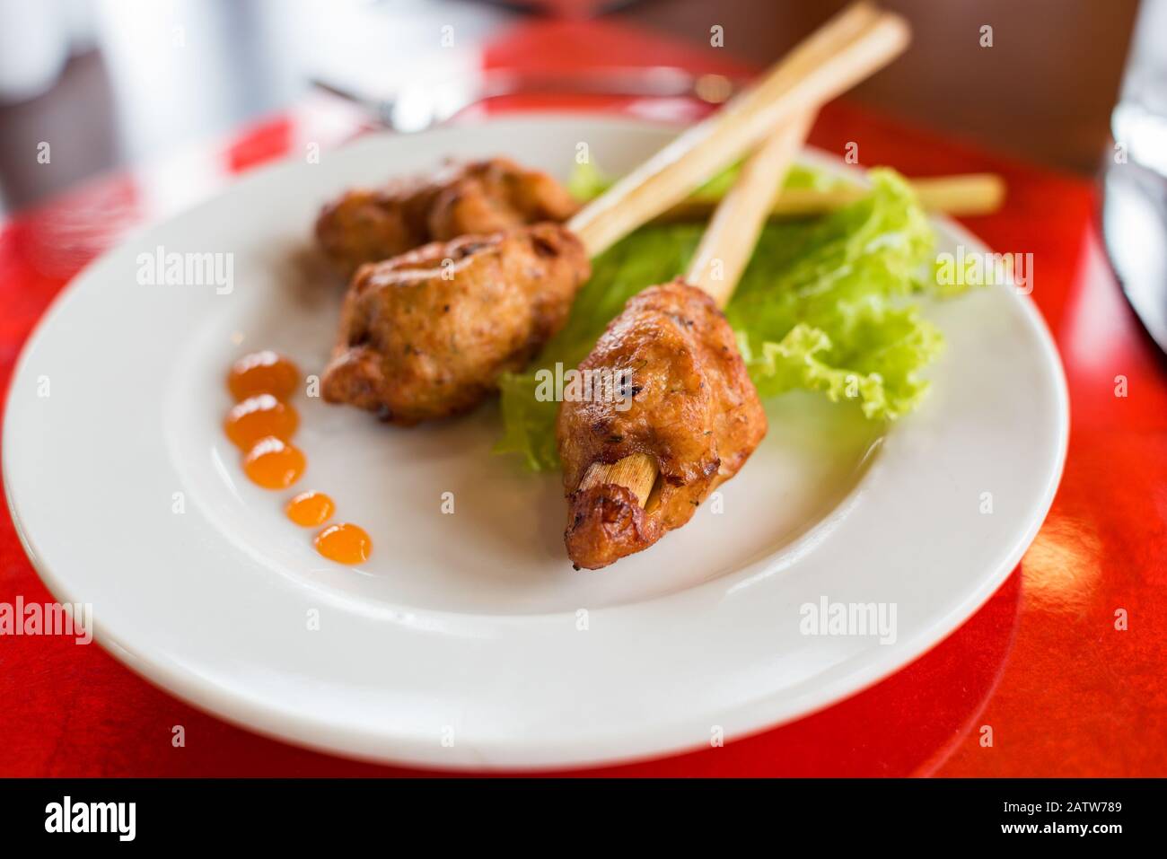 Fleisch auf einem Limongrasstab serviert mit Salat und heißer Chilisauce. Asiatische Restaurantmahlzeit Stockfoto