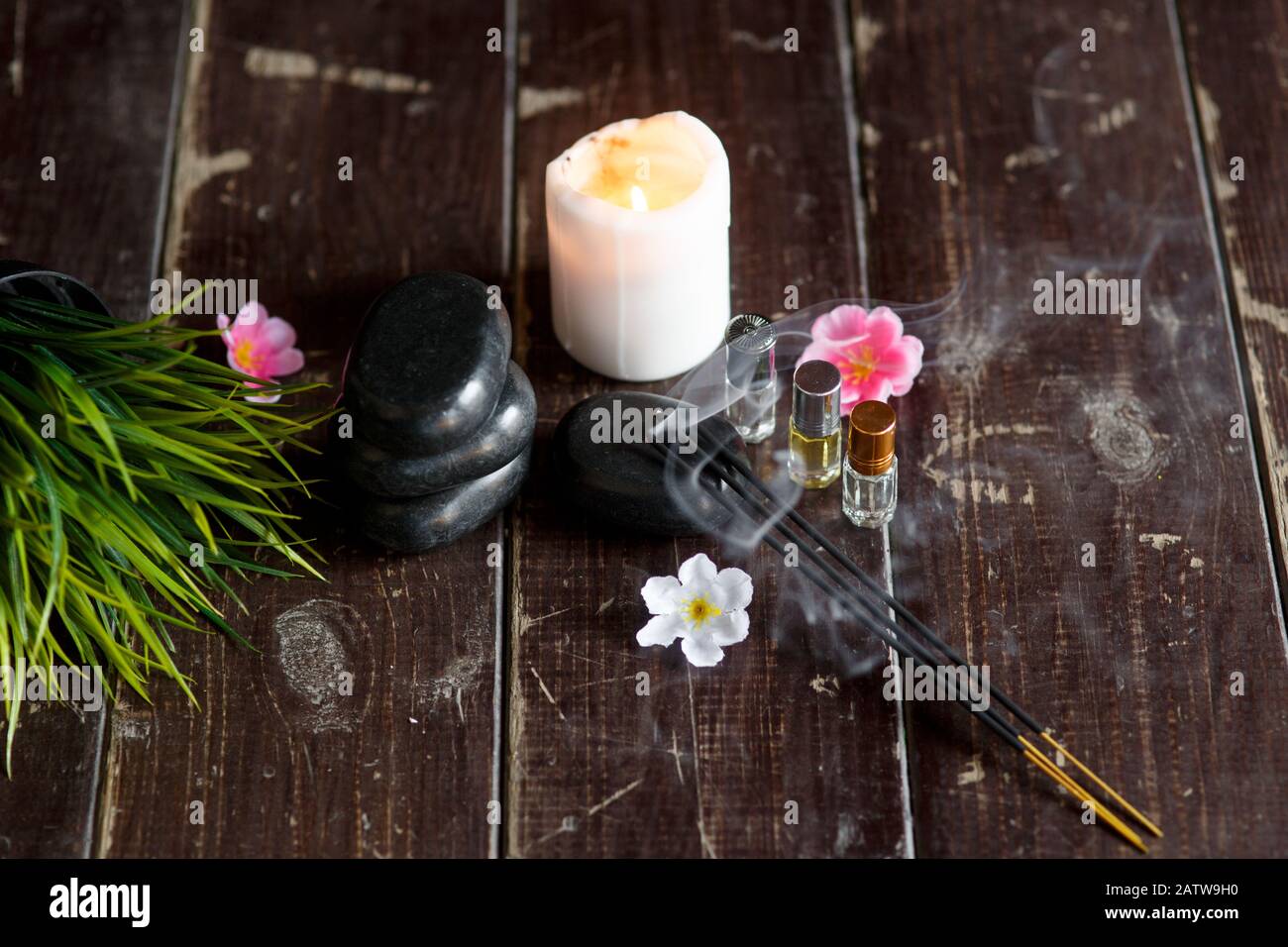 Massagesteine und Kerzennaht auf einem dunklen Holzhintergrund Stockfoto