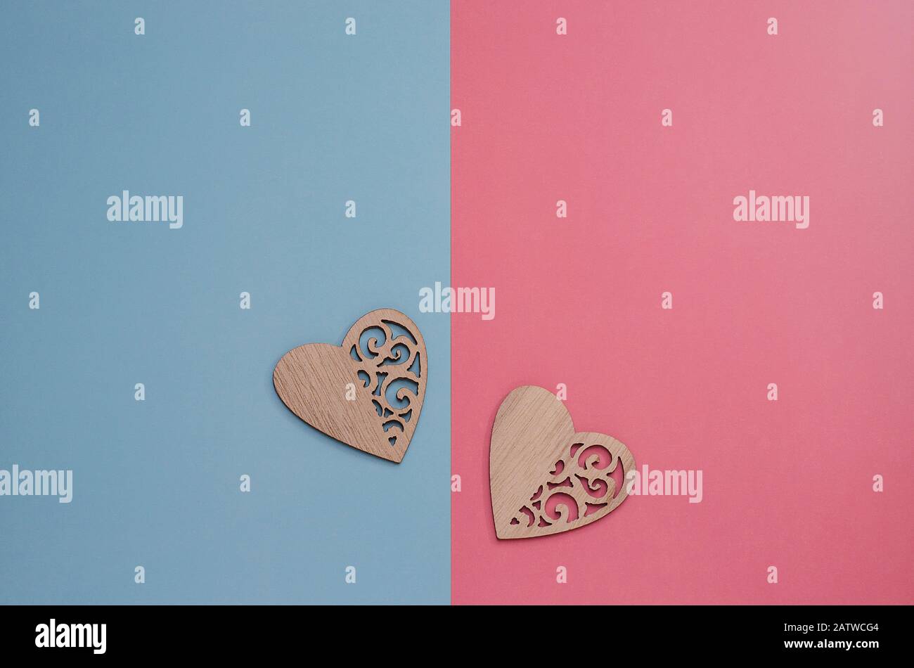 Zwei aus Holz geschnitzte Herzen auf pinkfarbenem und blauem Hintergrund mit Kopierraum. Hintergrundminimalismus zum Valentinstag, Muttertag, Geburt eines Kindes. Pos Stockfoto