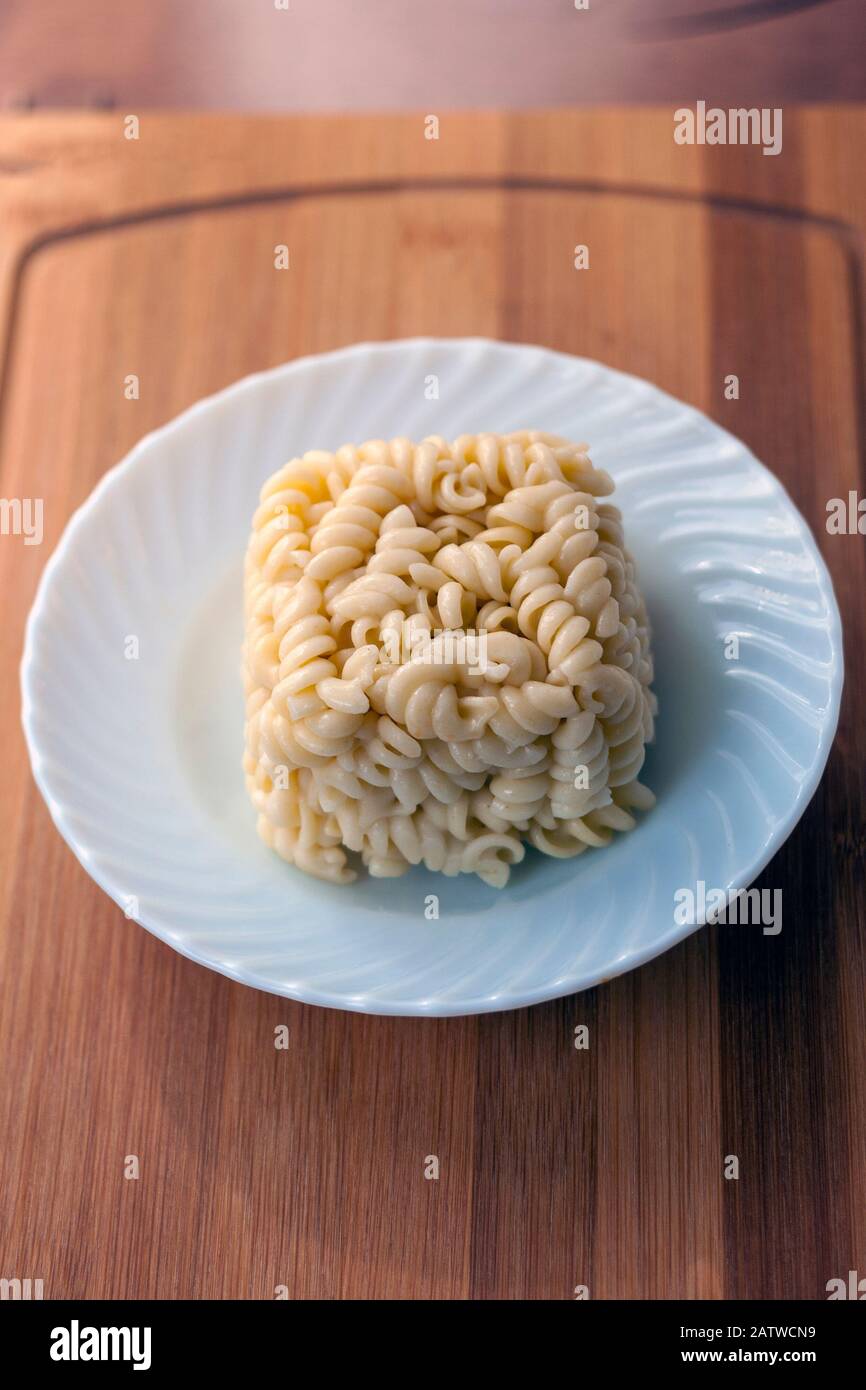 Kalte, lockig geformte Pasta, die wie ein Kuchenstück übrig geblieben ist Stockfoto