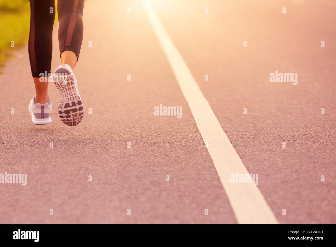 Nahaufnahme Der Sportlichen Frau, die bei Sonnenuntergang auf der Straße unterwegs ist. Fitness- und Workout Wellness-Konzept. Stockfoto