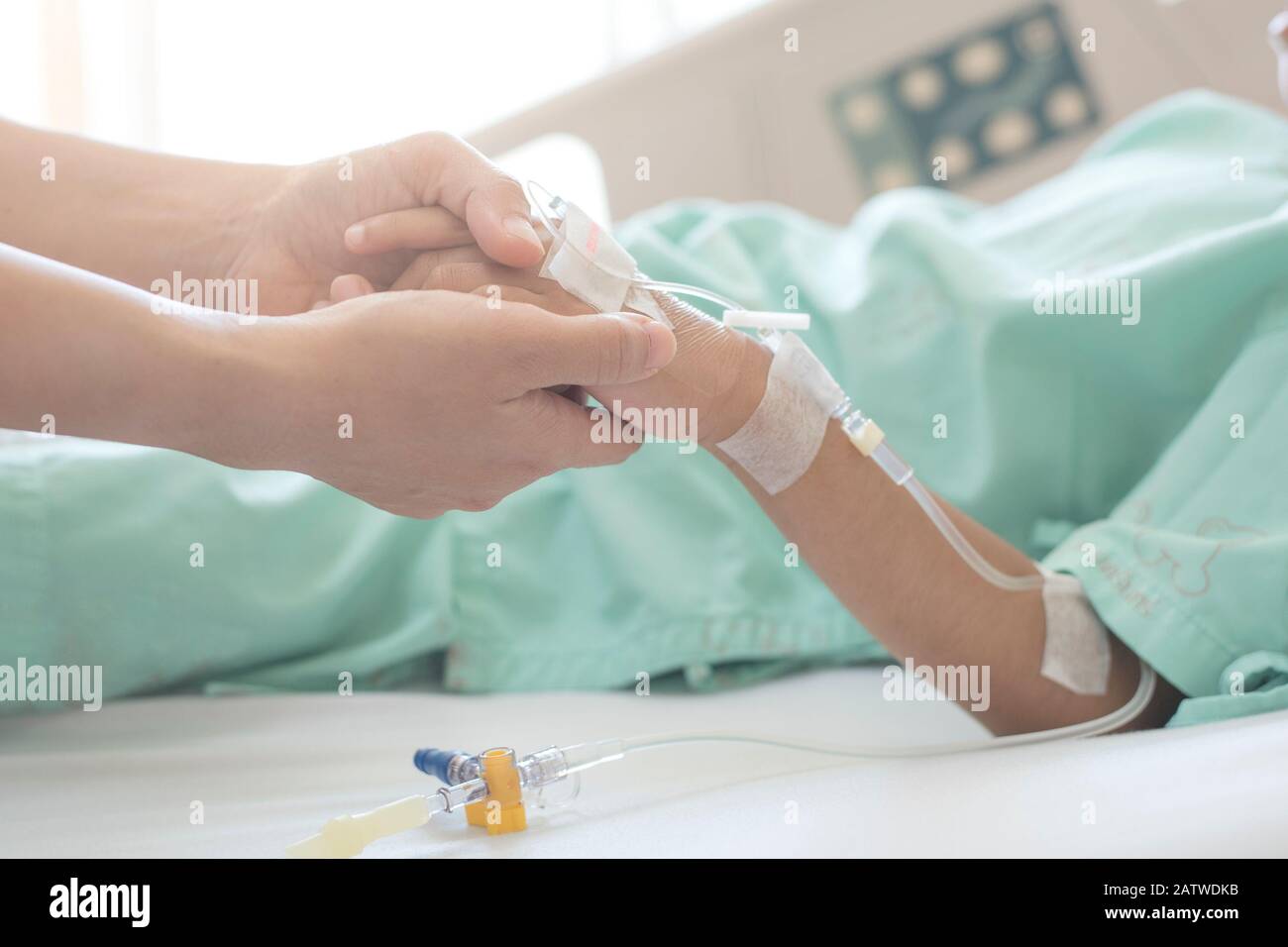 Medizinische Versorgung. Nahaufnahme der Hände der Mutter und des kranken kleinen Mädchens, das sich auf dem Sickbett im Krankenhaus zusammenhält, um Ermutigung zu geben. Stockfoto