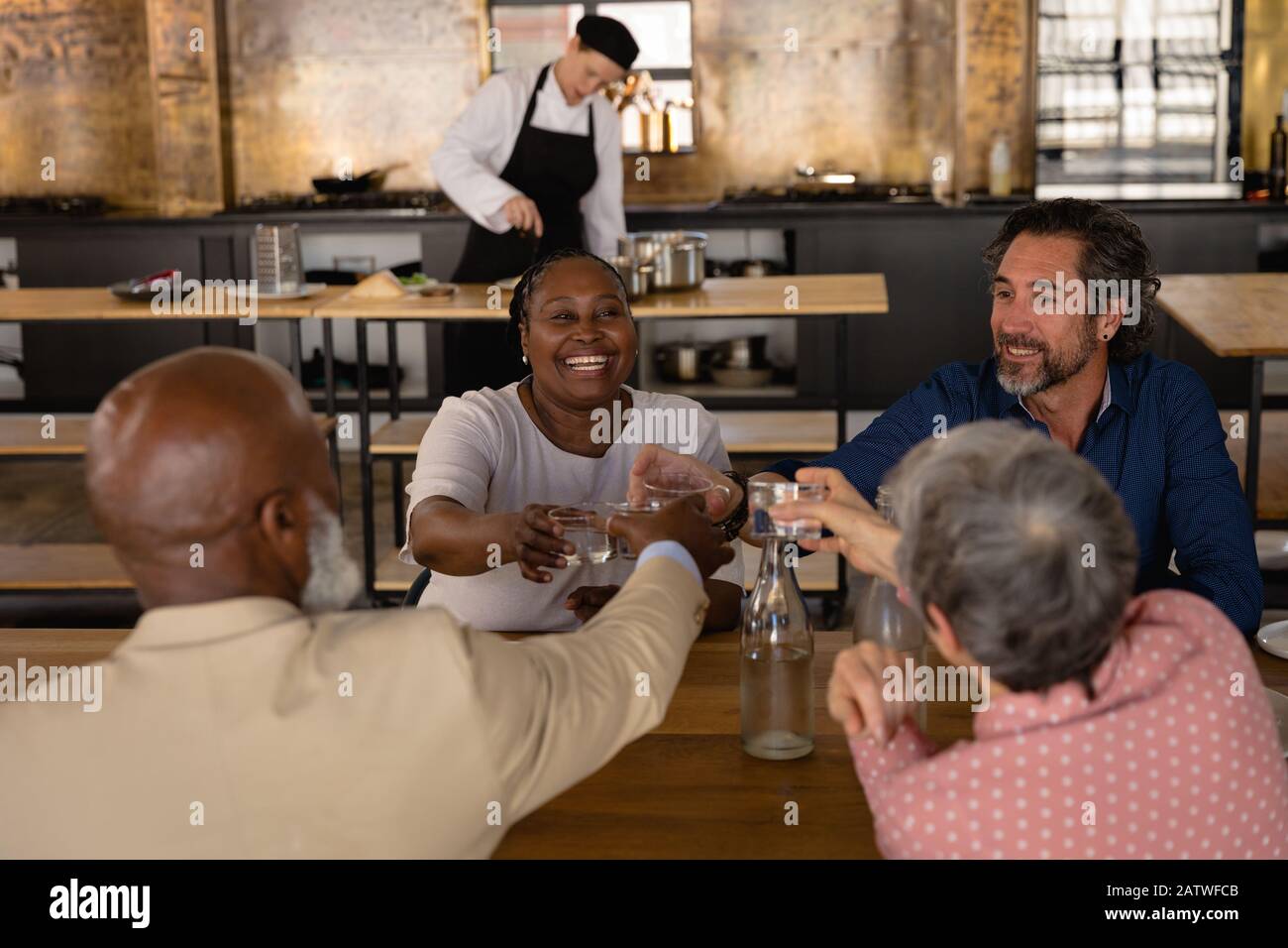 Freunde trinken zusammen, während sie hinter dem Kochen kochen Stockfoto