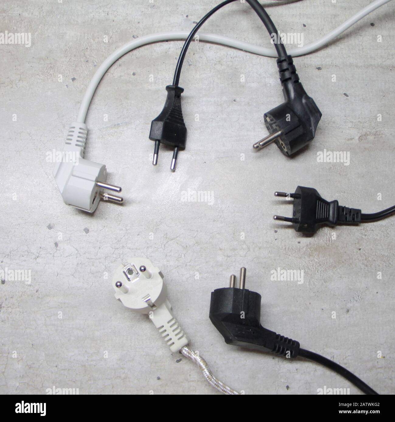 Elektrische Stecker mit Kabeln liegen auf einer grauen Oberfläche im Kreis. Stockfoto