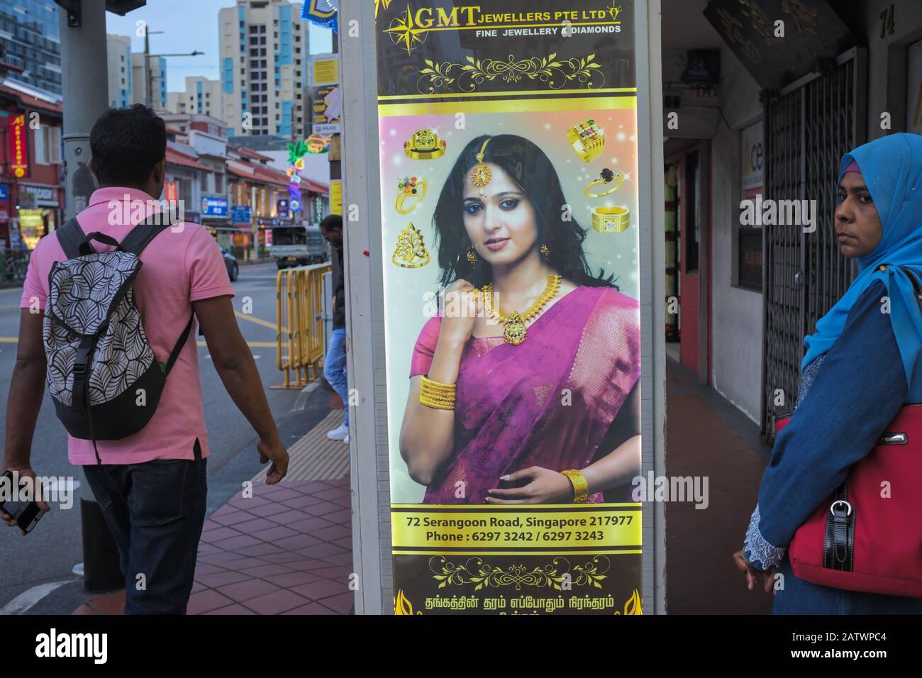 Eine ethnische Malaiische Frau (r) in der Serangoon Road, Little India, Singapur, neben einer beleuchteten Werbung für ein indisches Juweliergeschäft Stockfoto