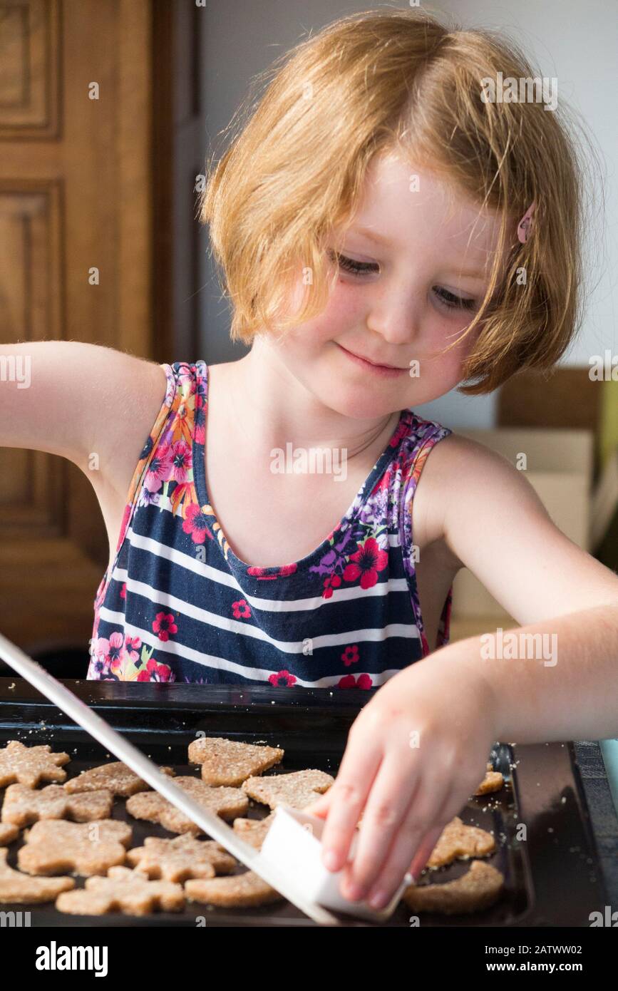 Mädchen im Alter von 5 / 5 Jahren, die ein Gebäckschneider beim Backen von Keksrezepten aus Zutaten/Keksen verwenden; Hauskochbacken mit Kindern/Kindern. (112) Stockfoto