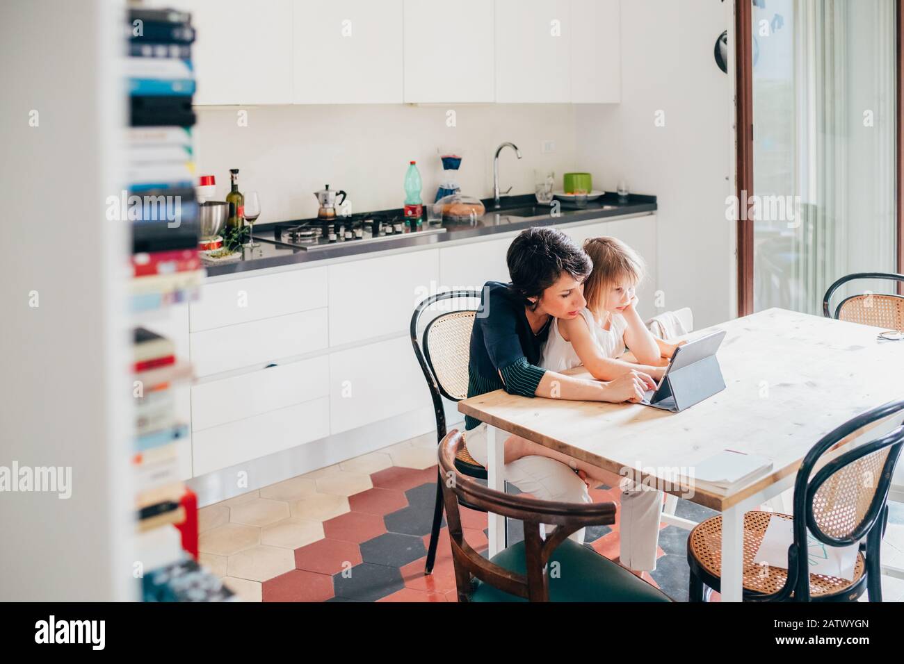 Mutter und Tochter drinnen mit Tablet-PC-Sitztisch - Lernen, Unterhaltung, Unterrichtskonzept Stockfoto