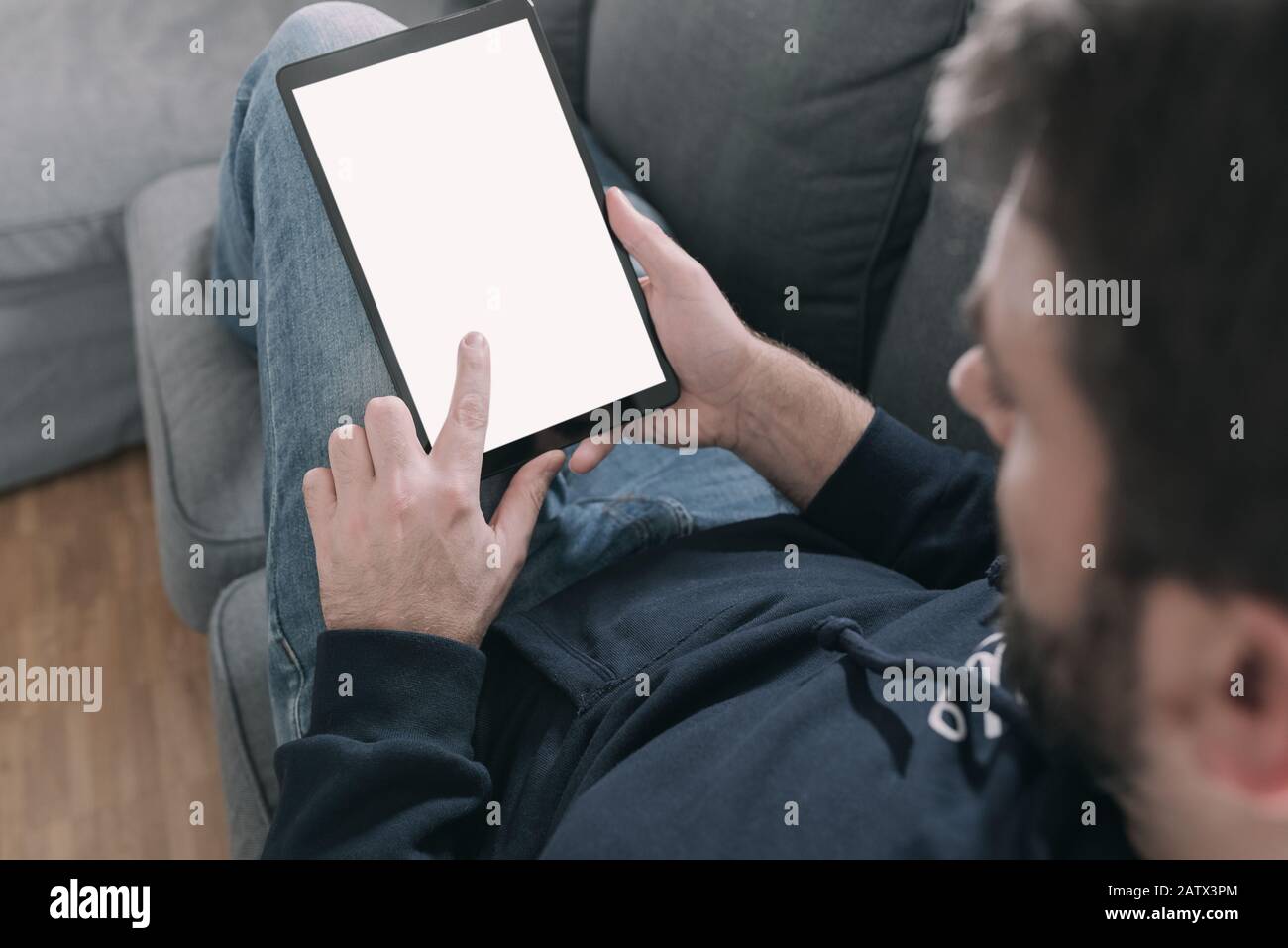 Mann, der sich auf dem Sofa entspannt, während er einen Tablet-Computer verwendet Stockfoto