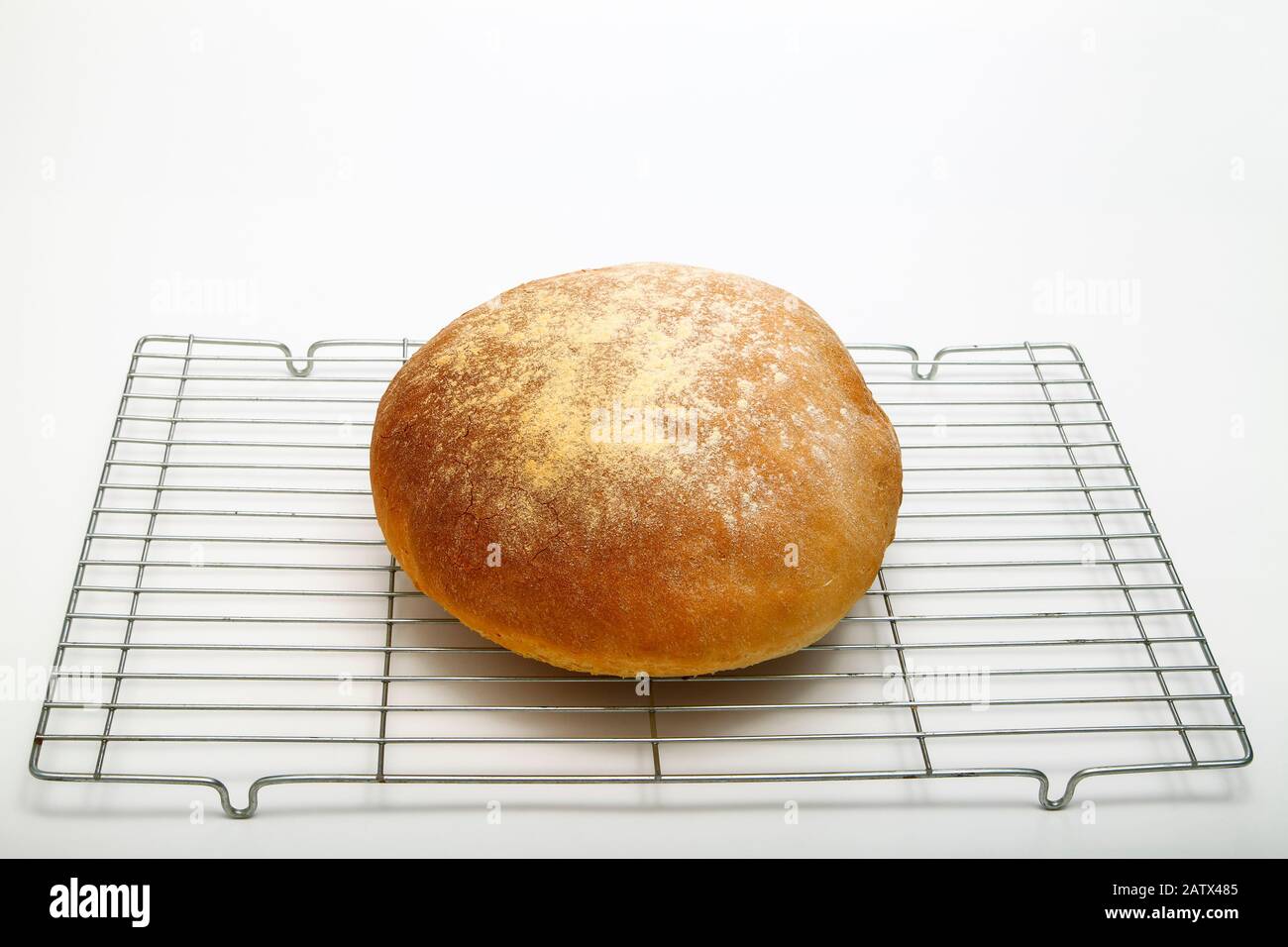 Frisch gebackenes Brotlaib auf einem Kühlregal, isoliert auf weißem Hintergrund Stockfoto