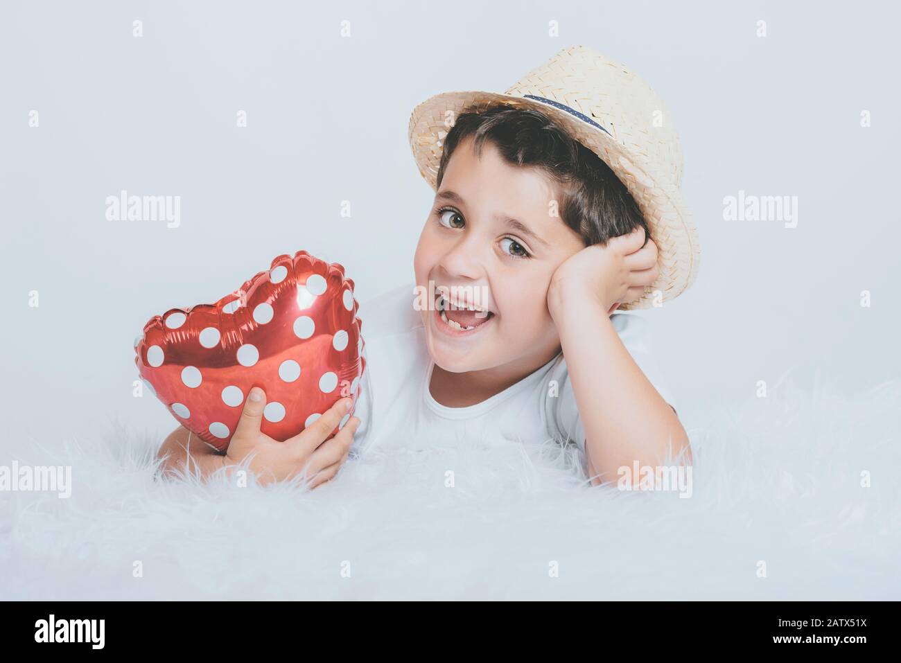 Lächelndes Kind mit herzförmigem Balloont auf weißem Hintergrund Stockfoto