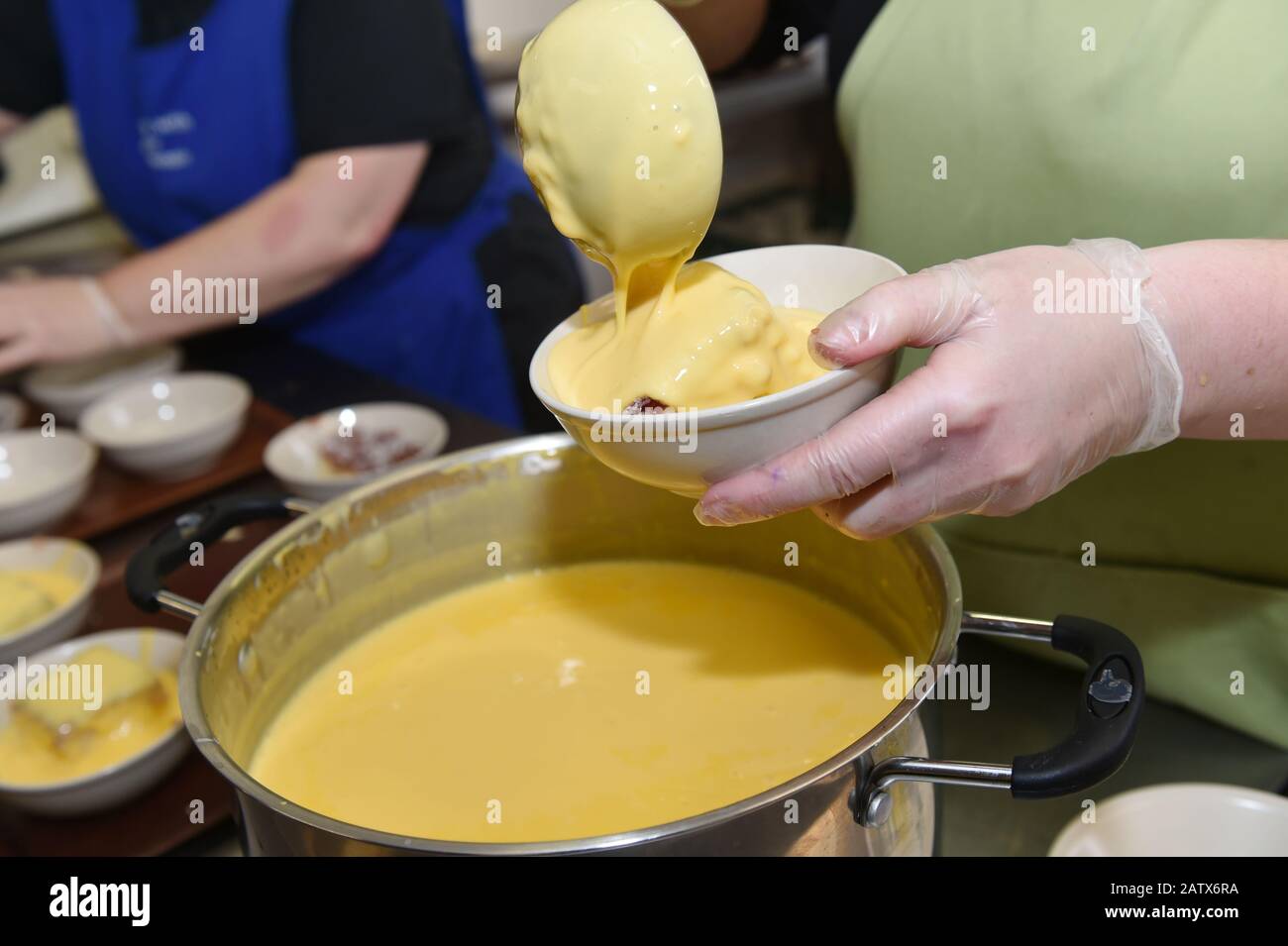 Custard wird in einem Drop-in-Center für ältere Menschen, Leeds UK, auf einen heißen Pudding geschüttet Stockfoto