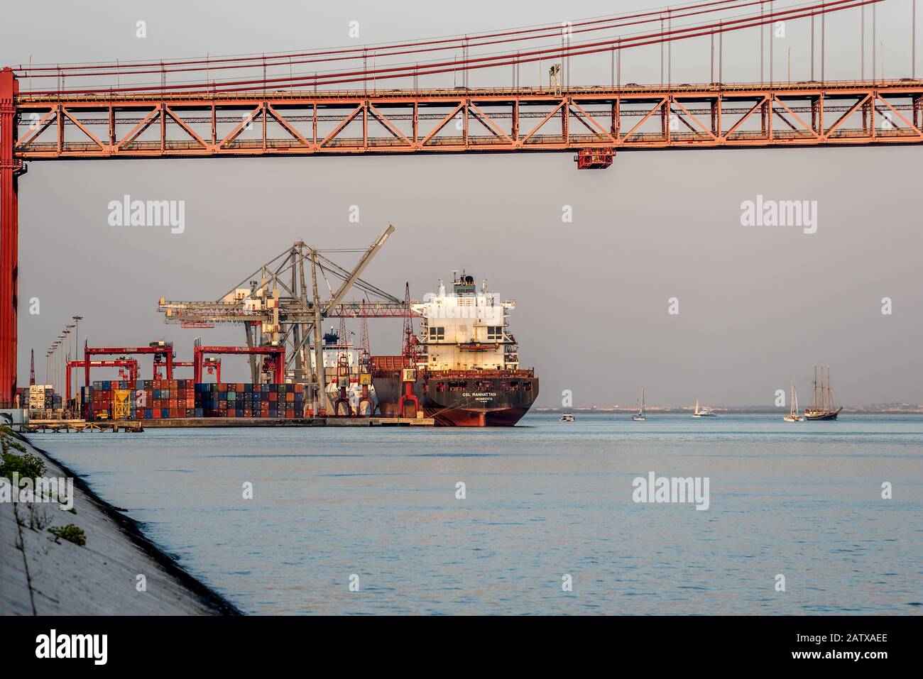 Containerschiff-Ladevorgang am Schiffsterminal auf dem Tejo neben der Brücke 25 de Abril in Alcantara Lissabon Portugal auf ruhiger See am Nachmittag Stockfoto