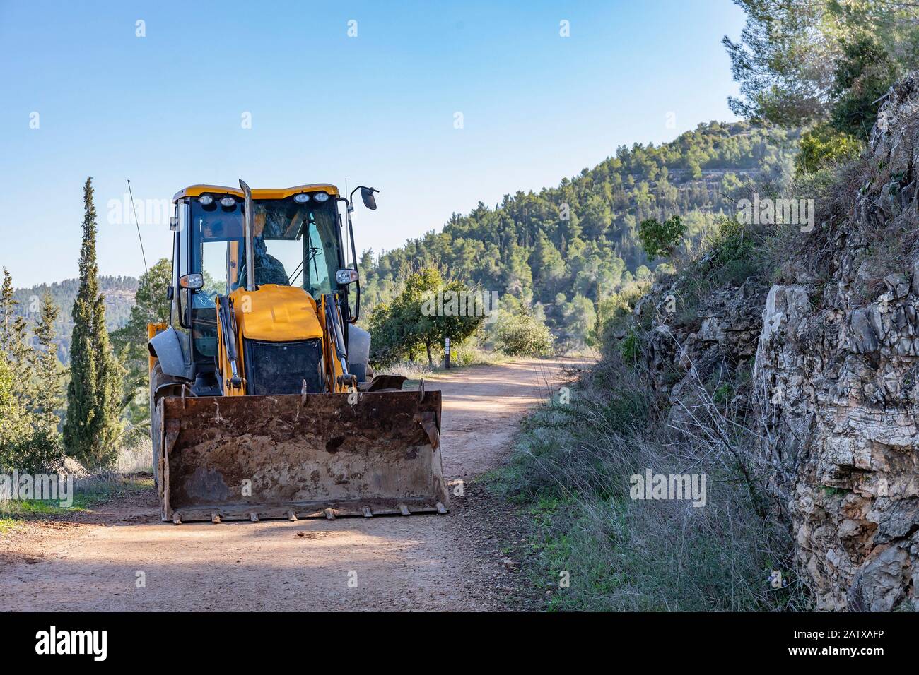 Ein Baggerlader, der auf einem Weg in einem Wald in der Nähe von Jerusalem, Israel, arbeitet Stockfoto