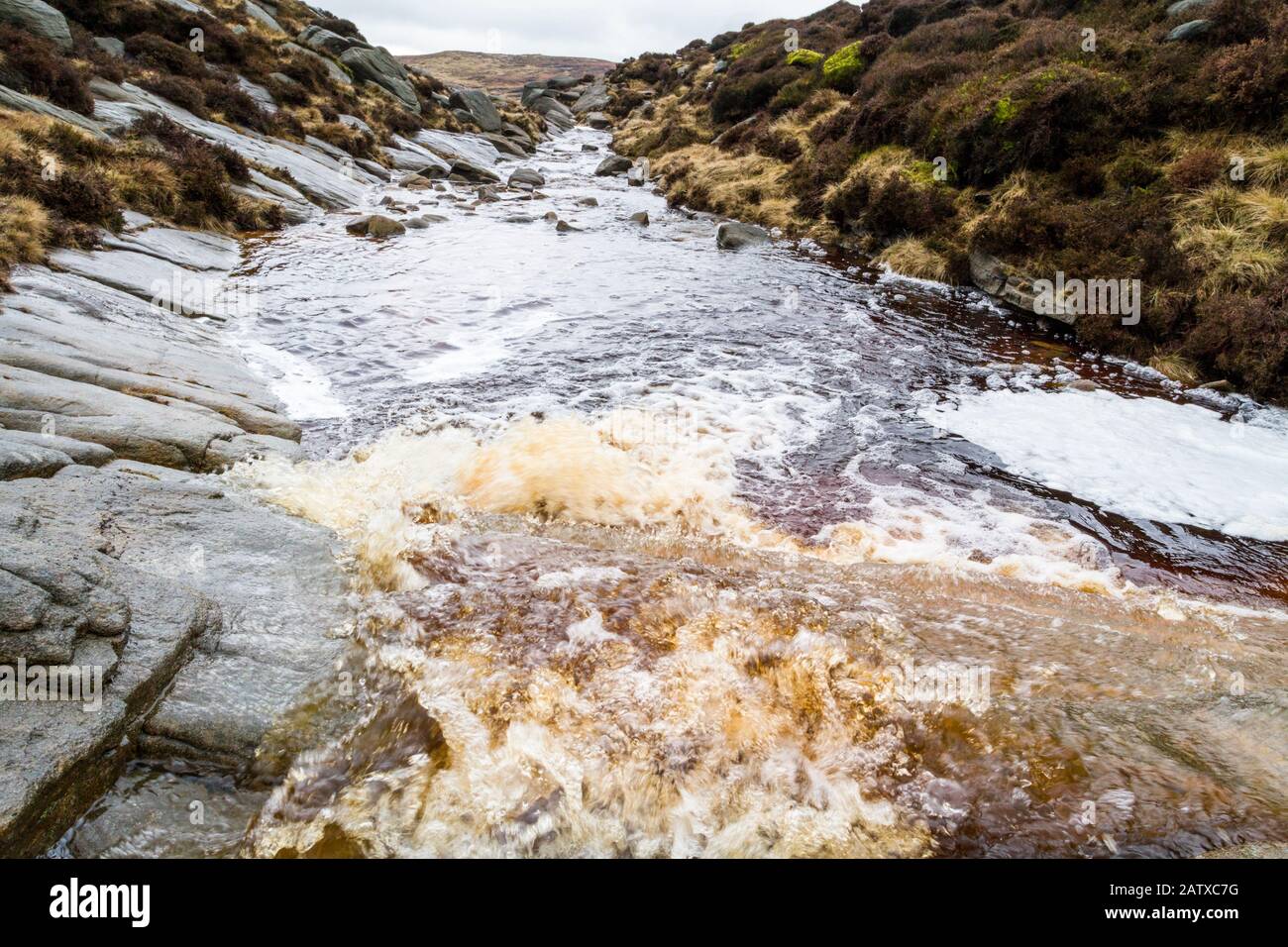 Moorbach aus verfärbenem Wasser. Die Verfärbung ist auf den durch Erosion vom Moorboden abgespülten Torf zurückzuführen. Kinder Scout, Derbyshire, England, Großbritannien Stockfoto