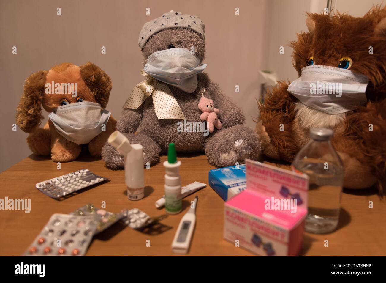 Spielzeuge in den medizinischen Masken mit Medikamenten und Tabletten auf dem Tisch Stockfoto