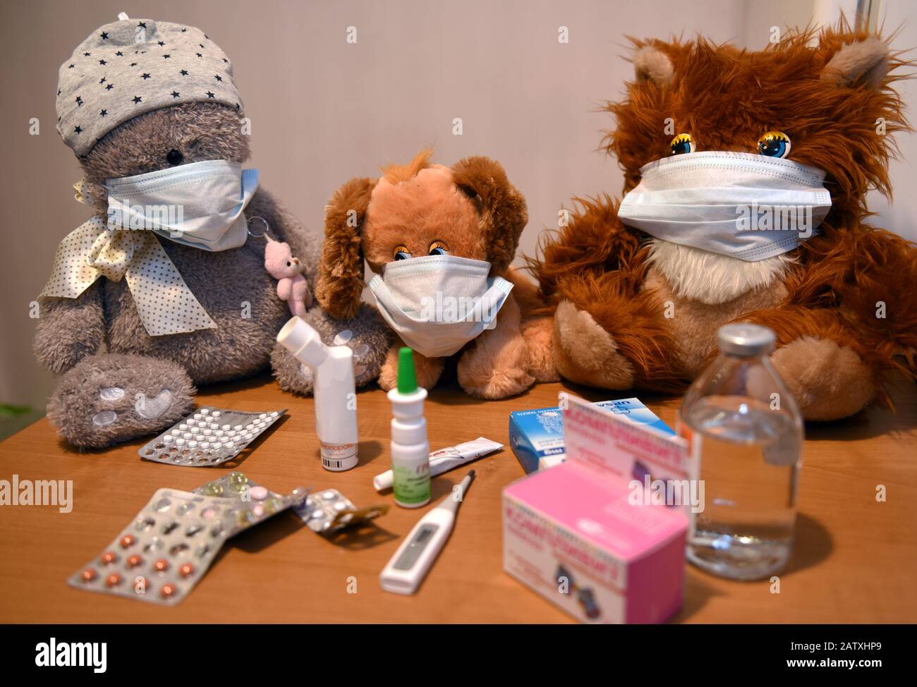 Spielzeuge in den medizinischen Masken mit Medikamenten und Tabletten auf dem Tisch Stockfoto