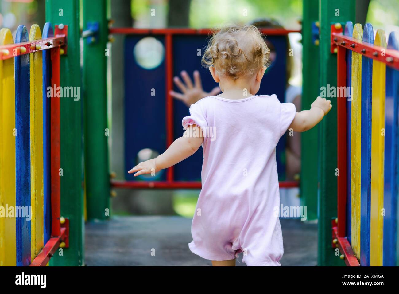 Auf dem Spielplatz spielt süßes Baby-Mädchen. Das einjährige Kind läuft zur Mutter. Stockfoto