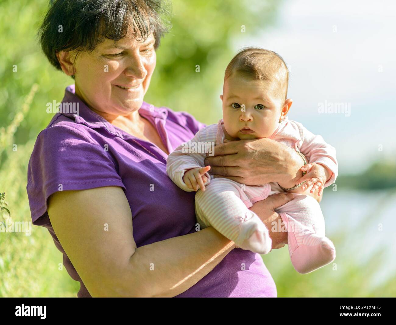 Baby-Mädchen an den Händen ihrer Großmutter in der Natur Stockfoto