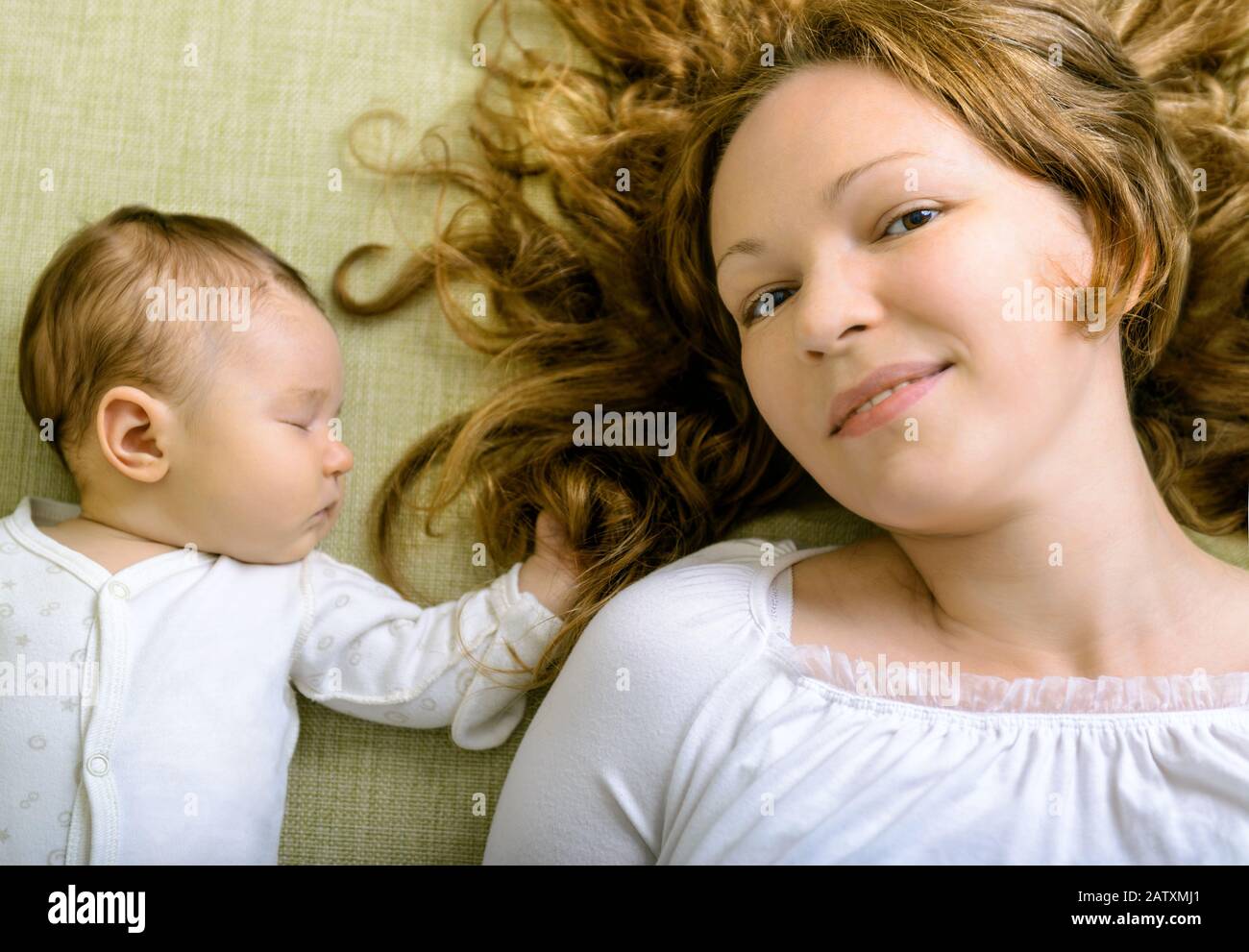 Schöne Frau und ihre neugeborene Tochter zu Hause auf der Couch Stockfoto