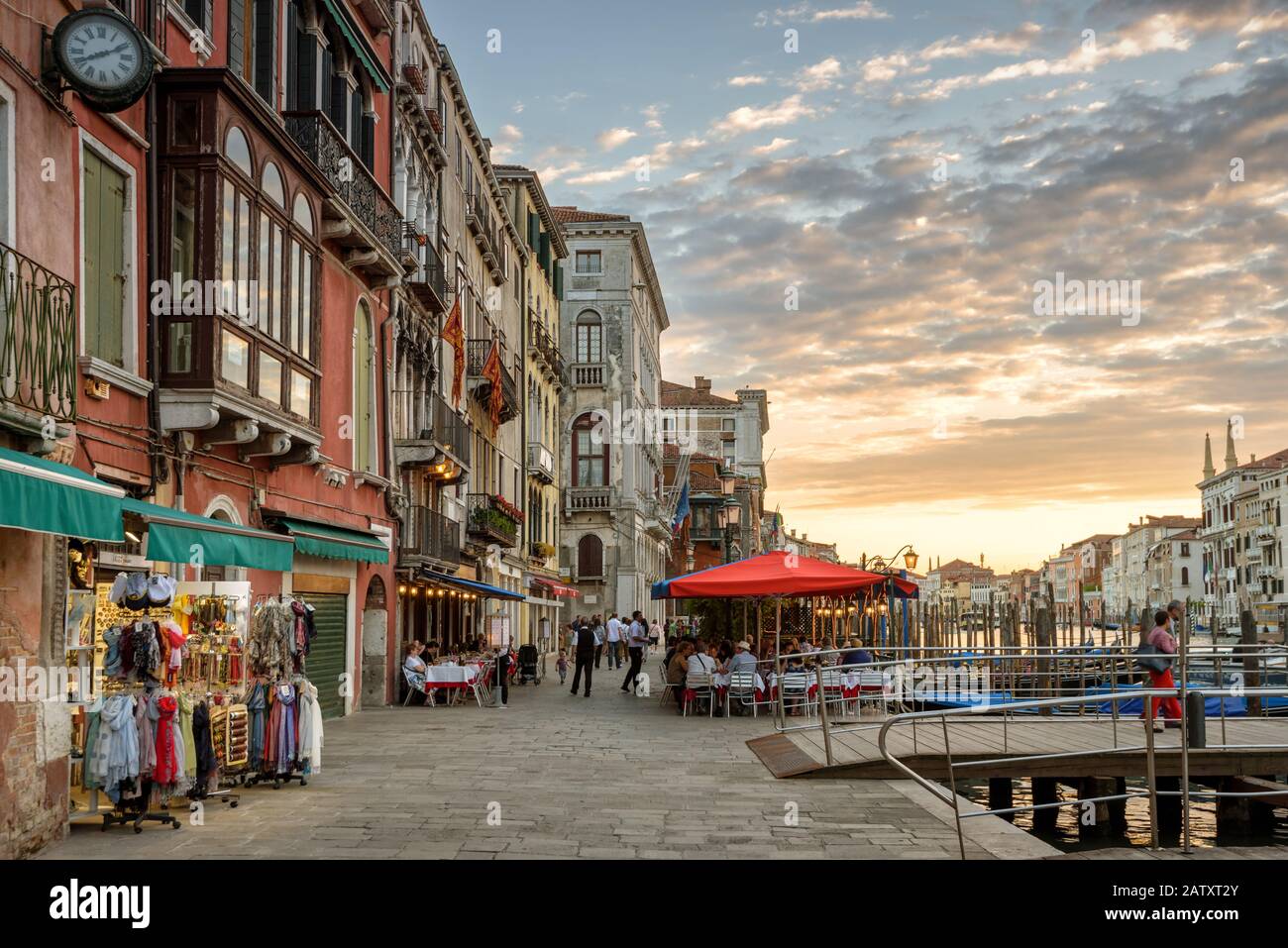 Canal Grande mit der alten Straße in Venedig bei Sonnenuntergang, Italien. Geschäfte, Restaurants und Pier am Wasser in Venedig. Stockfoto