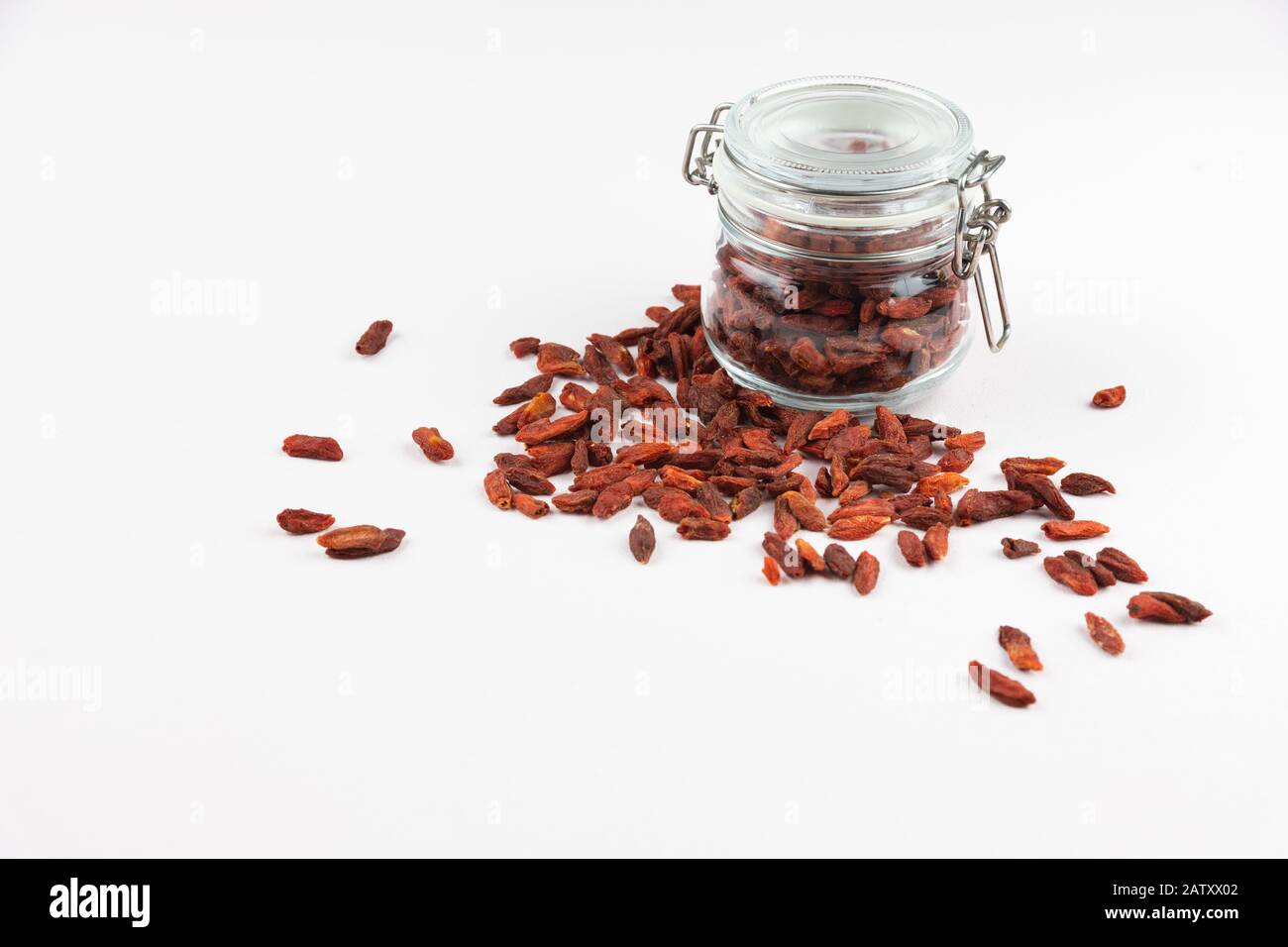 Glasbecher voller Goji-Beeren und mehr rote Beeren auf dem Tisch, isoliert auf weißem Hintergrund Stockfoto