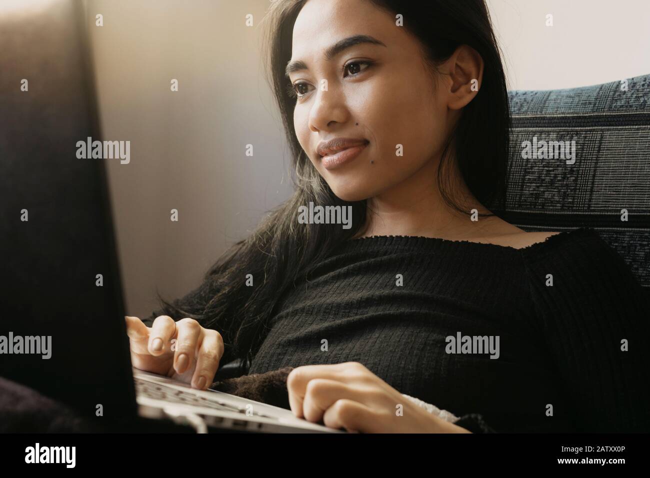 Schöne junge Frau, die zu Hause an einem Laptop arbeitet. Stockfoto