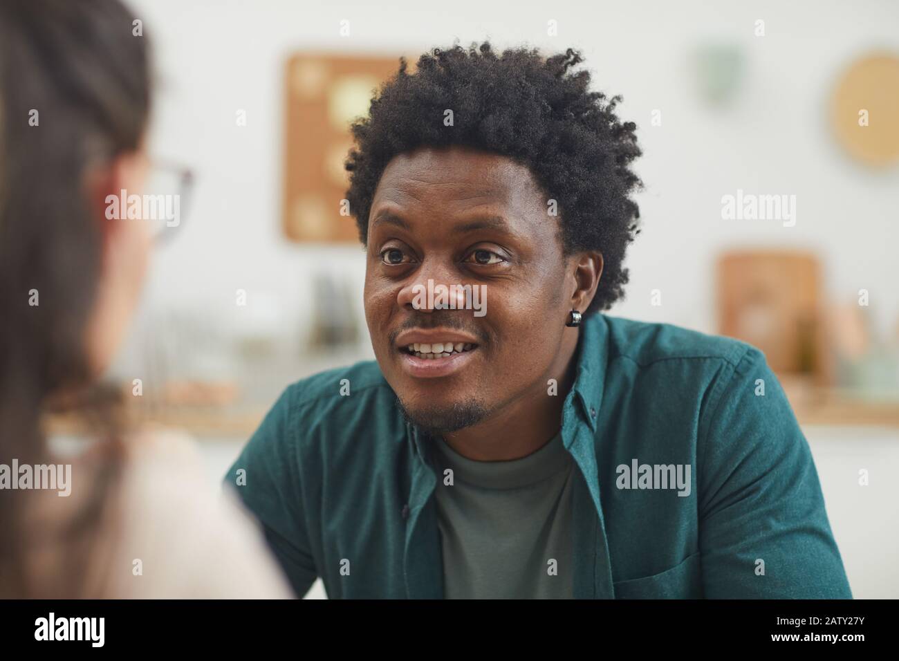 Junger afrikanischer Mann in legerer Kleidung lächelnd und talkrig für junge Frau Stockfoto