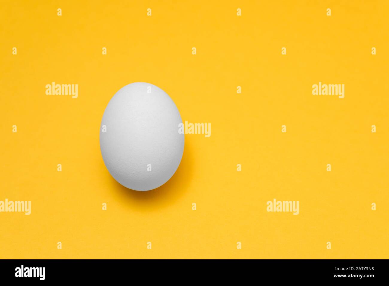 Ein weißes Ei auf gelbem Hintergrund auf der linken Seite für Designs, visuelle Kunst für ostern werben Stockfoto