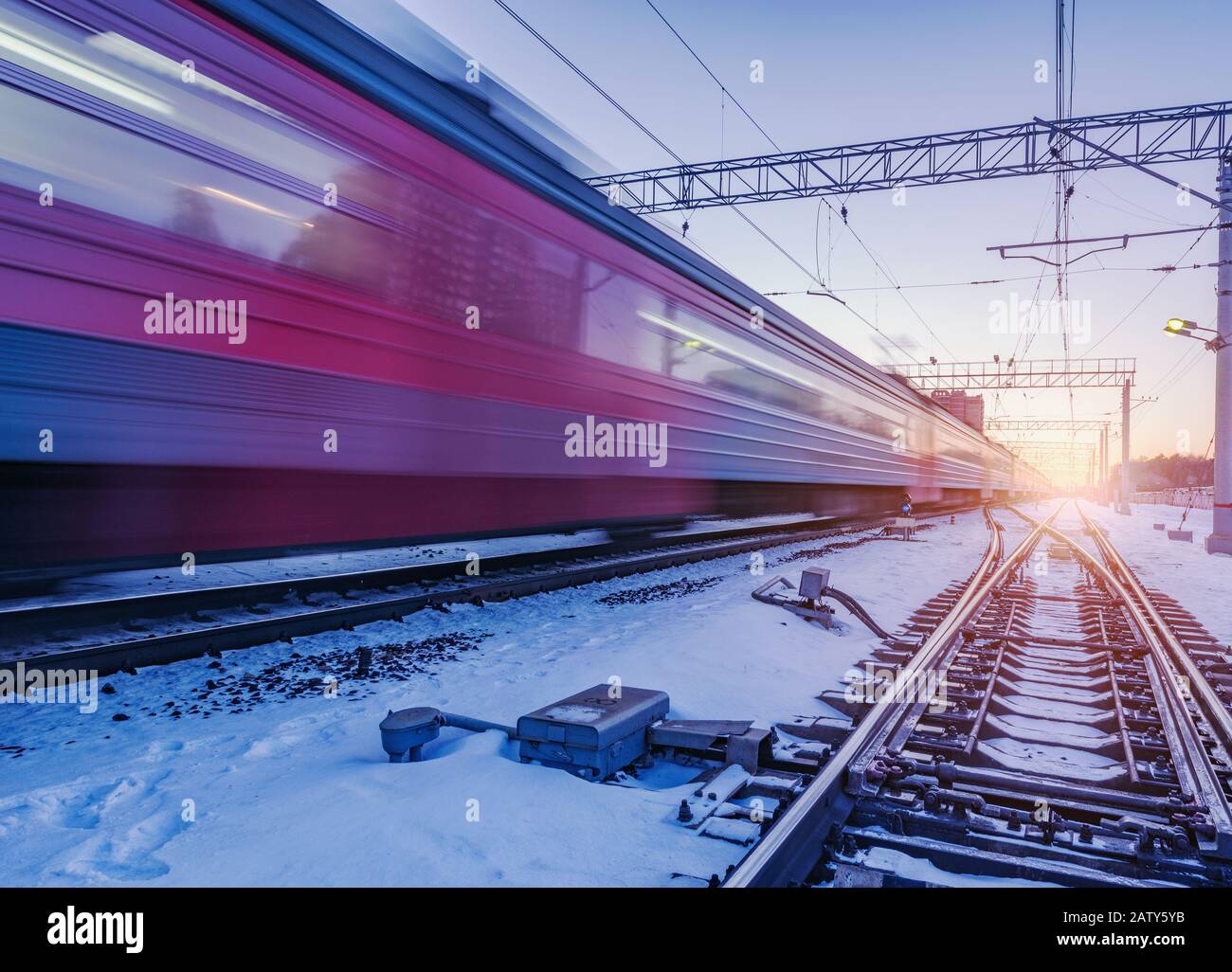 Der Hochgeschwindigkeitszug fährt bei Sonnenuntergang schnell durch den Bahnhof. Stockfoto