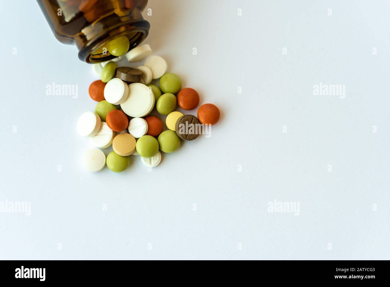 Medikamente und Pillen. Mehrfarbige Medikamente auf weißem Hintergrund Nahaufnahme. Braune Glasflasche mit den darin befindlichen Pillen auf weißem Hintergrund. Mehrfarbig Stockfoto