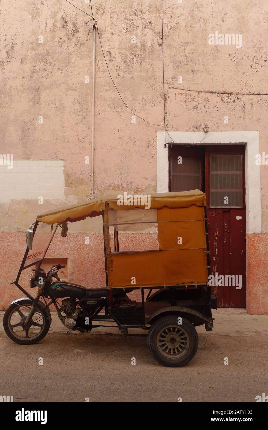 Pedicab (Fahrradtaxi) auf einer kolonialen Straße in Hunucma, Yucatan, Mexiko. Papel Picado-Flaggen fliegen über den Kopf. Stockfoto