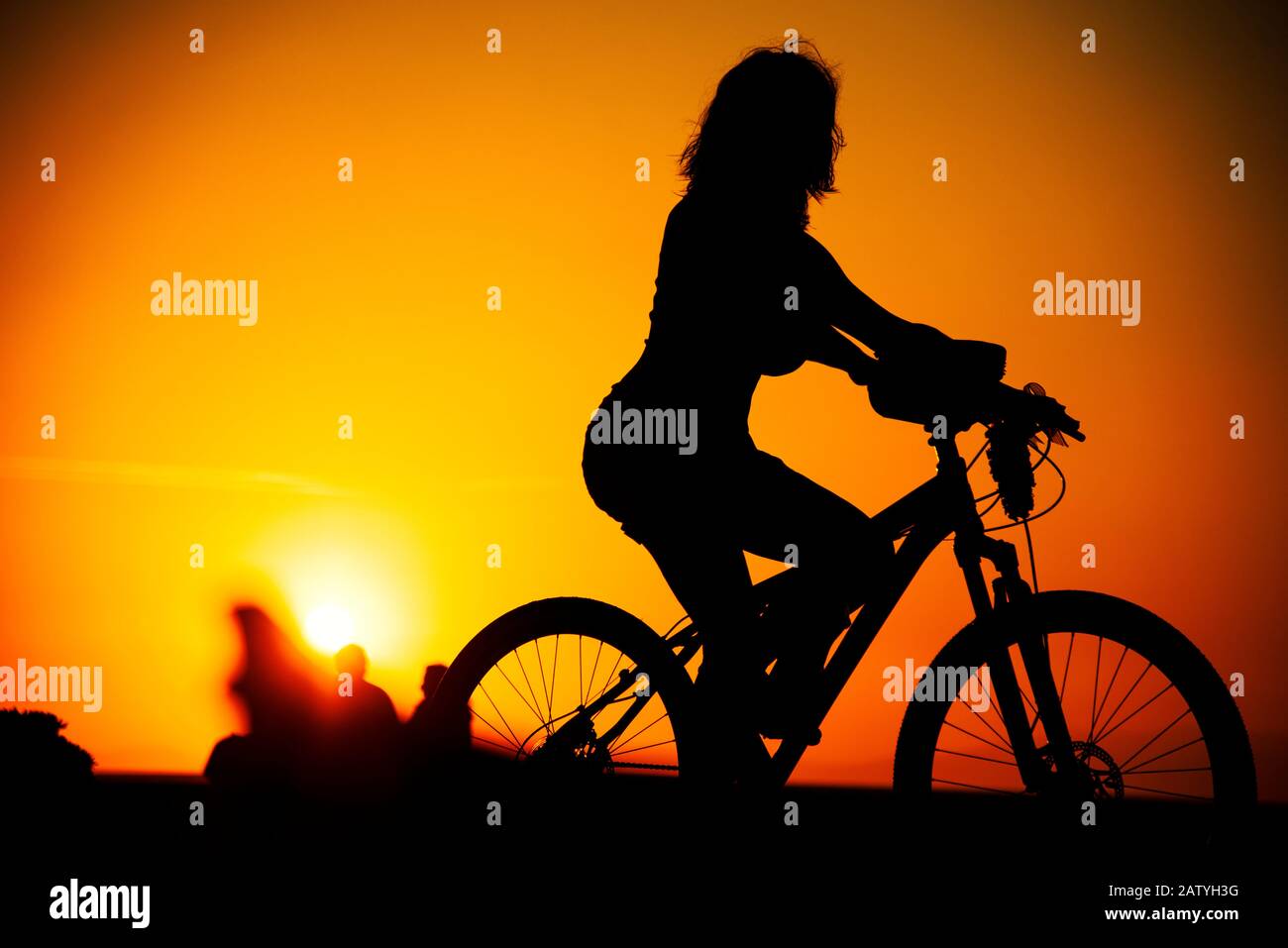 Silhouette Frau mit einem Fahrrad bei Sonnenuntergang in Izmir Stockfoto
