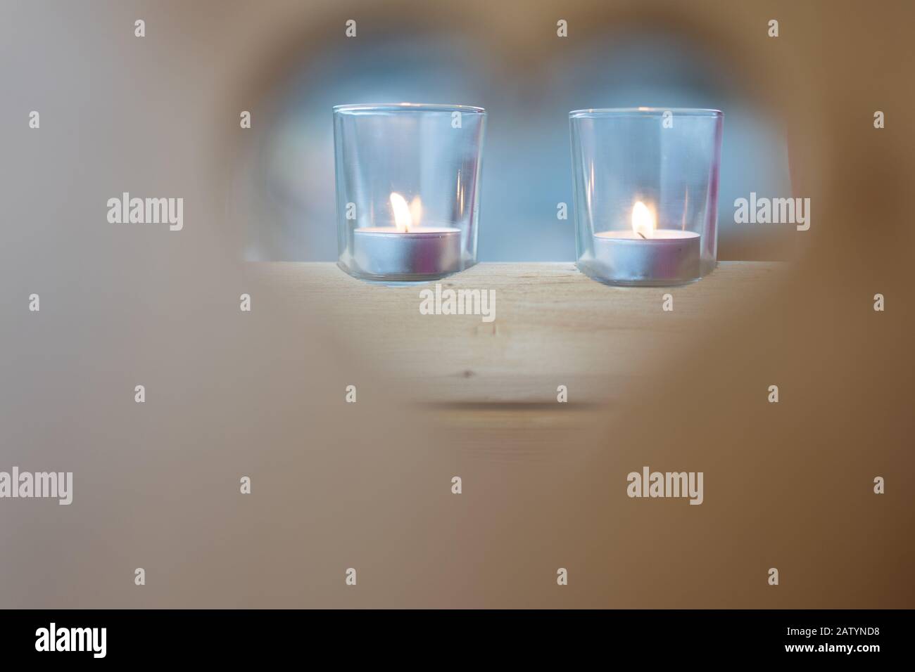 Herzförmige Rahmen am Valentinstag, verschwommenes Peephole im Holzstuhl, fokussiertes Kerzenglas im Hintergrund, Nahaufnahme. Stockfoto