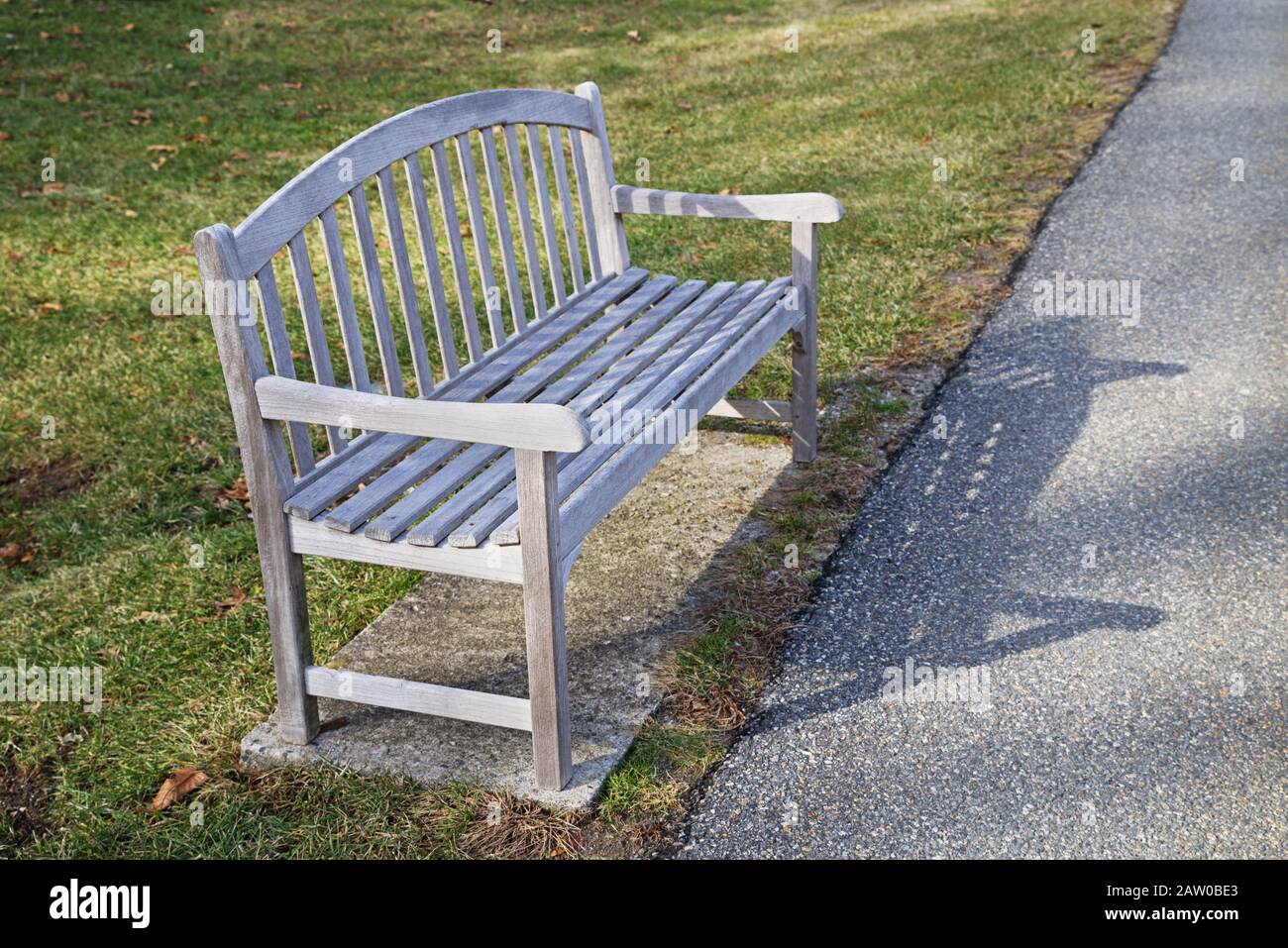 Holzparkbank auf einem Asphaltweg Stockfoto