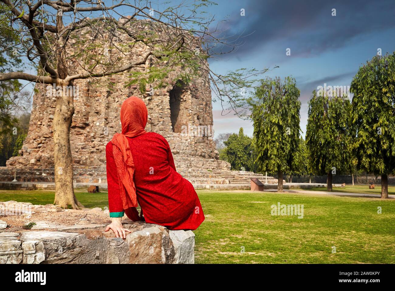 Indische Frau in rotem Kleid in der Nähe des Qutub Minar Turms in Delhi, Indien Stockfoto