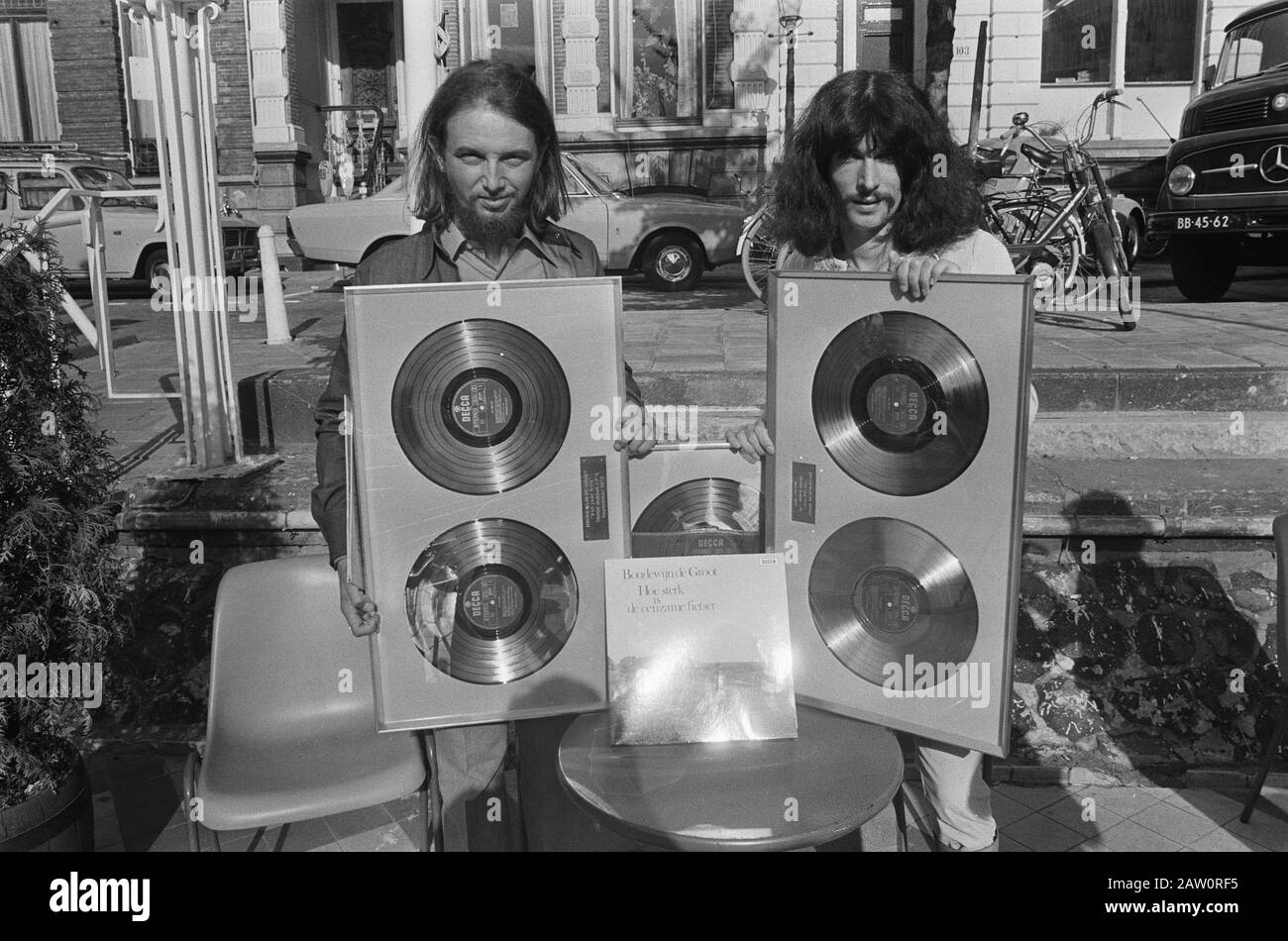 Boudewijn de Groot (rechts) und der Lyriker Lennaert Nijgh mit Platin-Schallplatten für das Album how Stronger is the Lone Rider; Hinweis: Die Labels bei den Platin-Schallplatten sind eindeutig der Text Fünf Jahre Hit 70.000 Doppel-LPs September 1972 (Nijgh) und fünf Jahre 100.000 Hits Doppel-LPs Januar 1973 (De Groot) zu lesen; von wie stark der Alleinfahrer hier ist nur das Albumcover ausgestellt. Die gezeigten Platin-/Goldplatten haben bereits Platten ausgegeben. Welcher wie stark der Alleinfahrer ist, wurde später vergeben. Siehe diese Liste .; Stockfoto