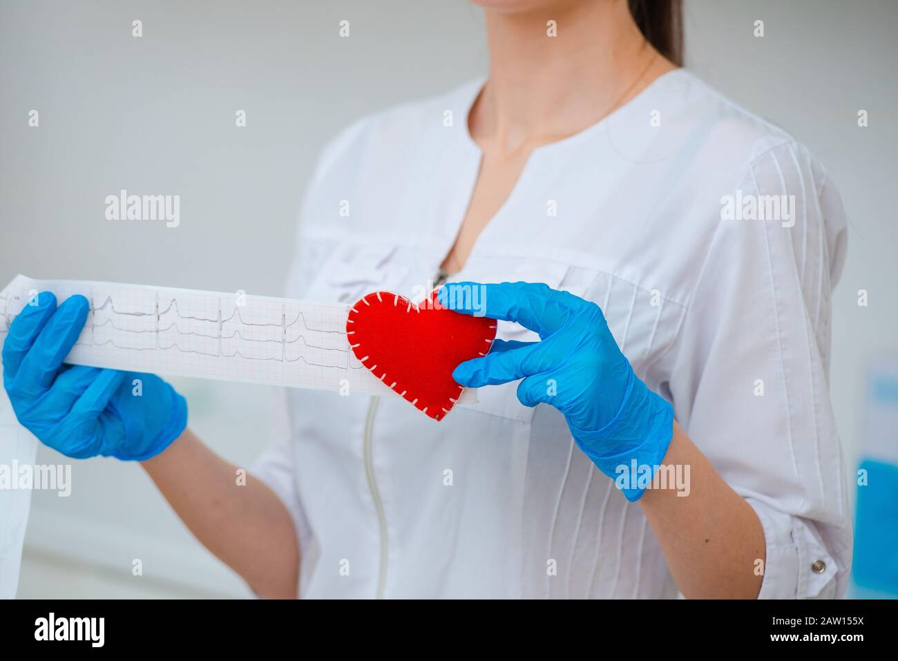 Kardiogramm des Herzens. Arzt mit einem Kardiogramm-Papierband und einem roten Herz in den Händen. Messwerte des Elektrokardiographen Stockfoto