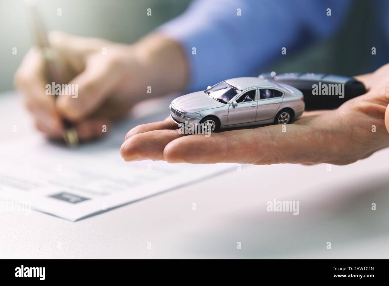 Kaufen Sie ein neues Autokonzept - Skalenmodell und Schlüssel in der Hand des Händlers Stockfoto
