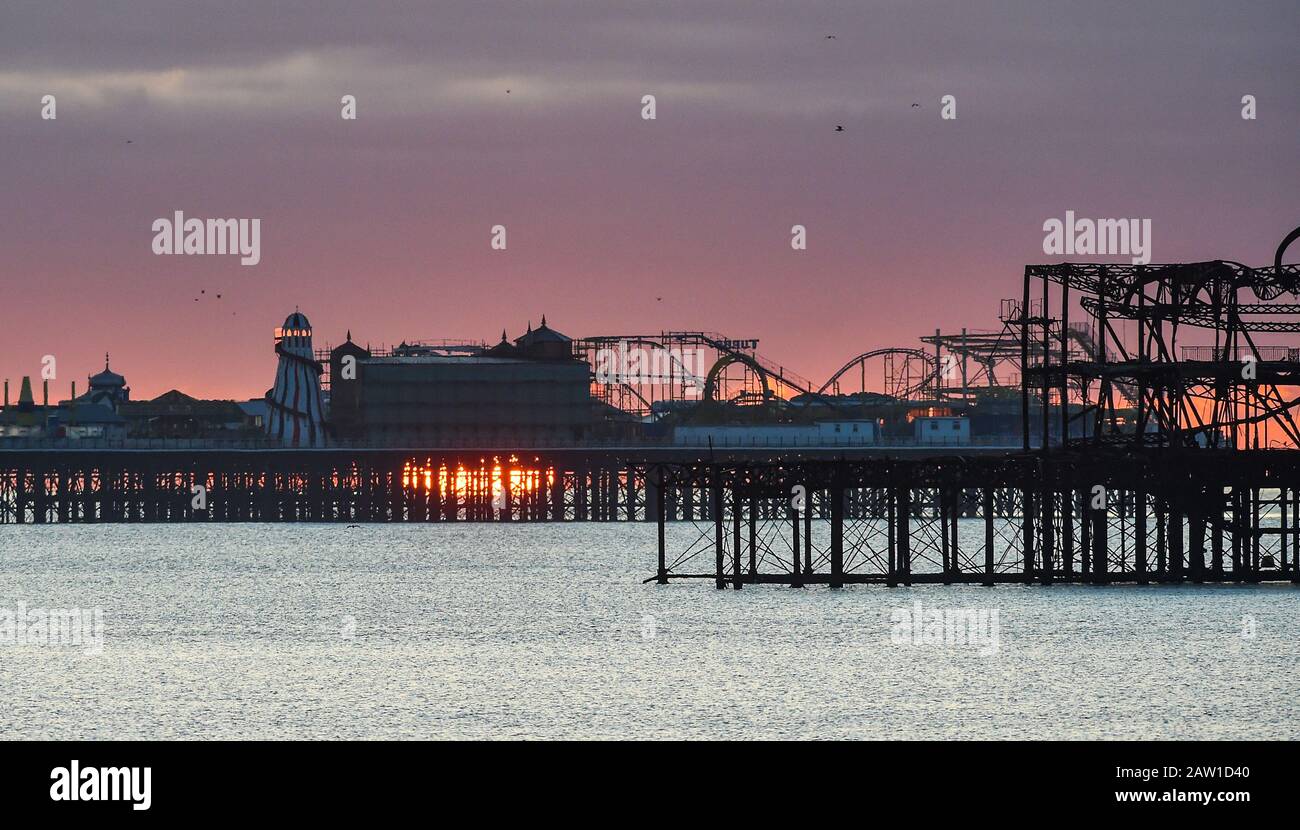 Brighton UK 6. Februar 2020 - Die Sonne steigt hinter Brightons zwei Piers an einem kalten hellen Morgen auf. Für die nächsten paar Tage wird in Großbritannien ein noch feineres Wetter prognostiziert, bevor das stürmische Wetter am Wochenende eintreffen wird. Kredit: Simon Dack / Alamy Live News Stockfoto