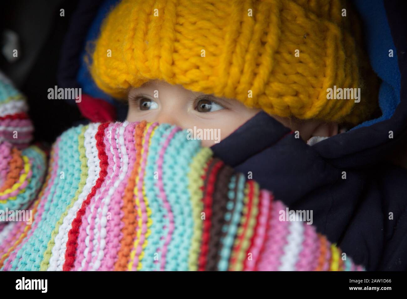 Nahaufnahme eines 6 Monate alten Babys, das gegen das kalte Wetter warm in den Buggy eingewickelt ist. UK Stockfoto